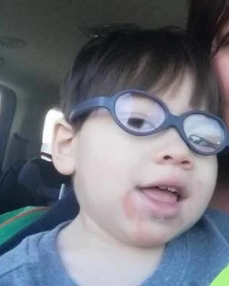 A young boy wearing glasses with a slight smile
