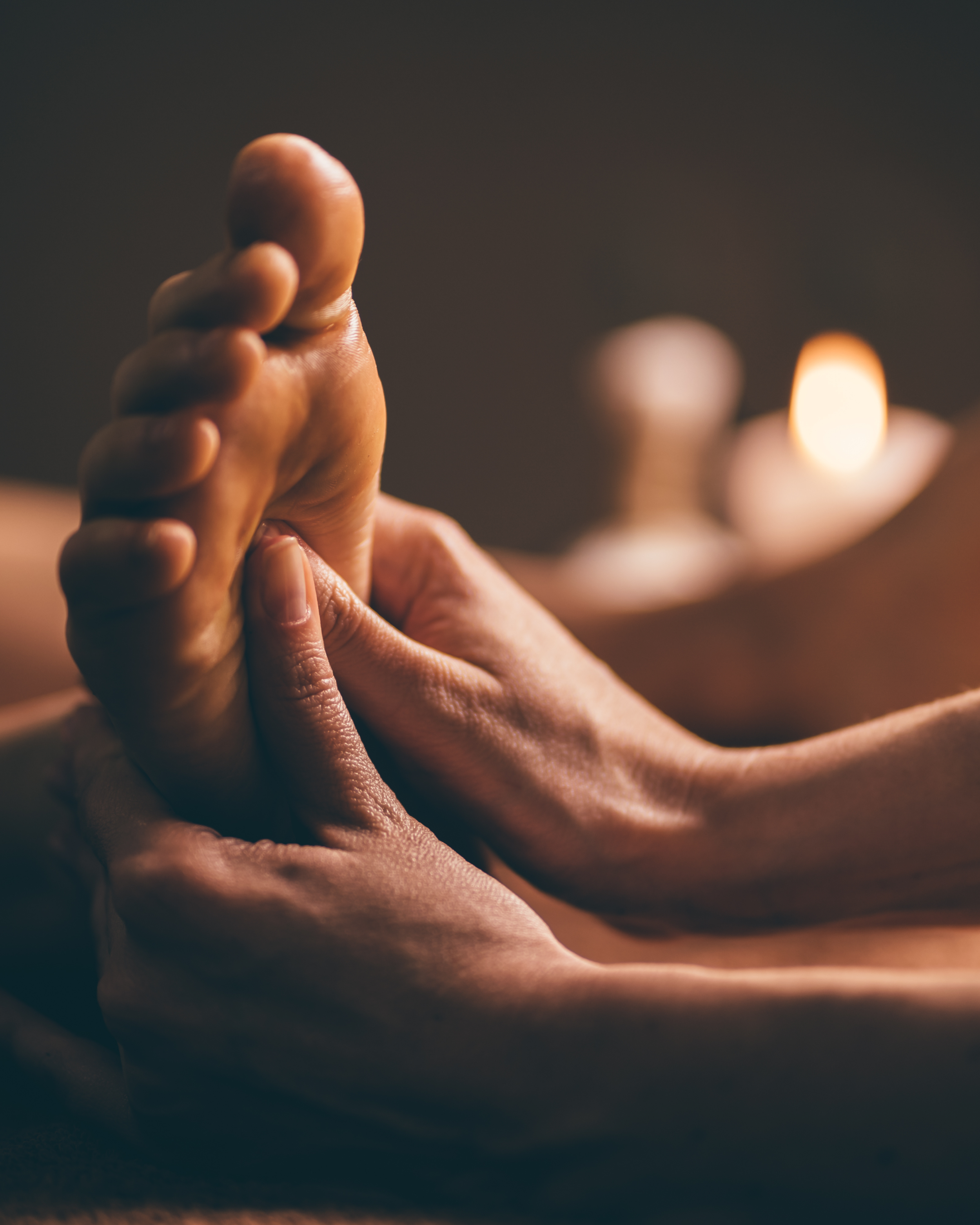 Mains d'une personne recevant un massage relaxant dans un environnement paisible avec des bougies