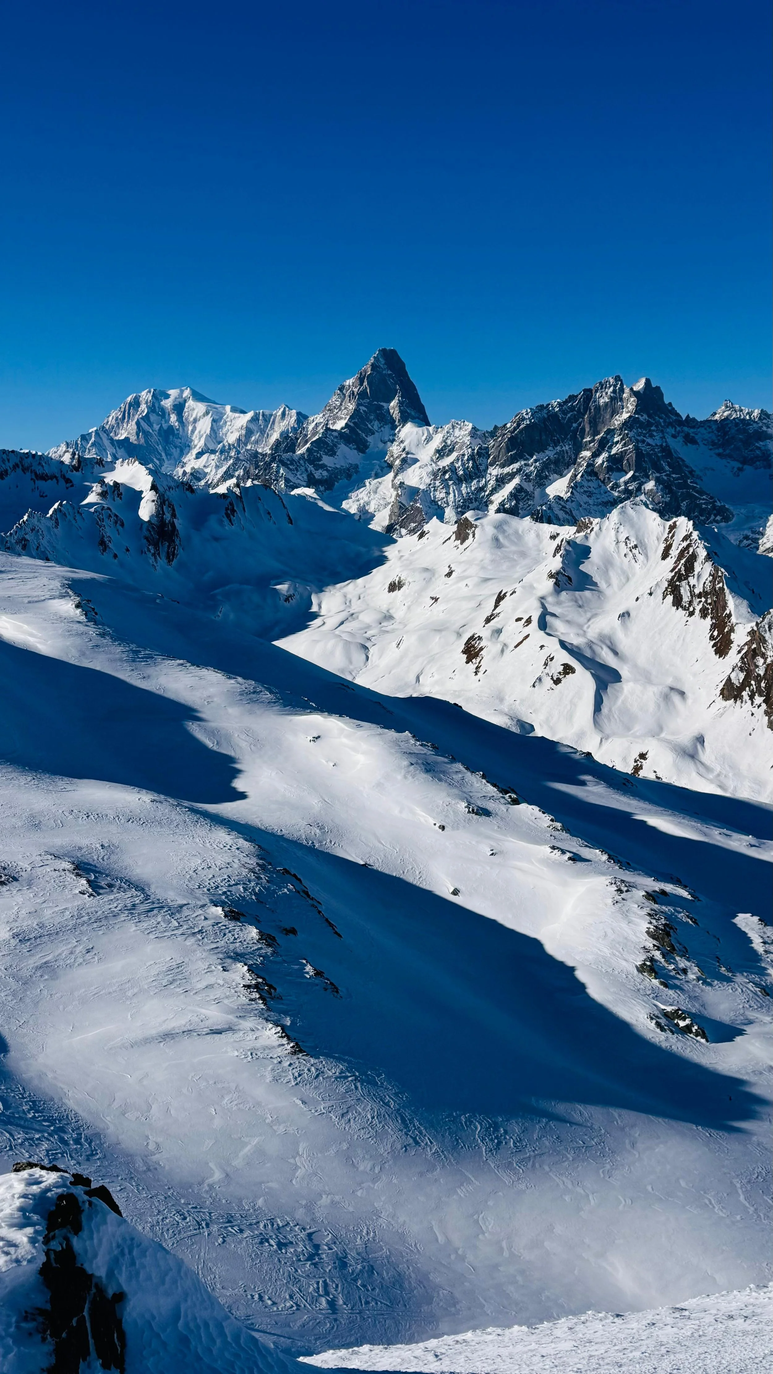Chaînes de montagnes enneigées sous un ciel bleu clair.