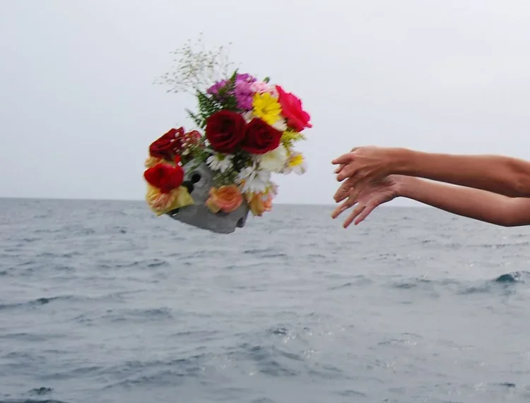 A decorated urn with flowers tossed from the rail of schooner clearwater