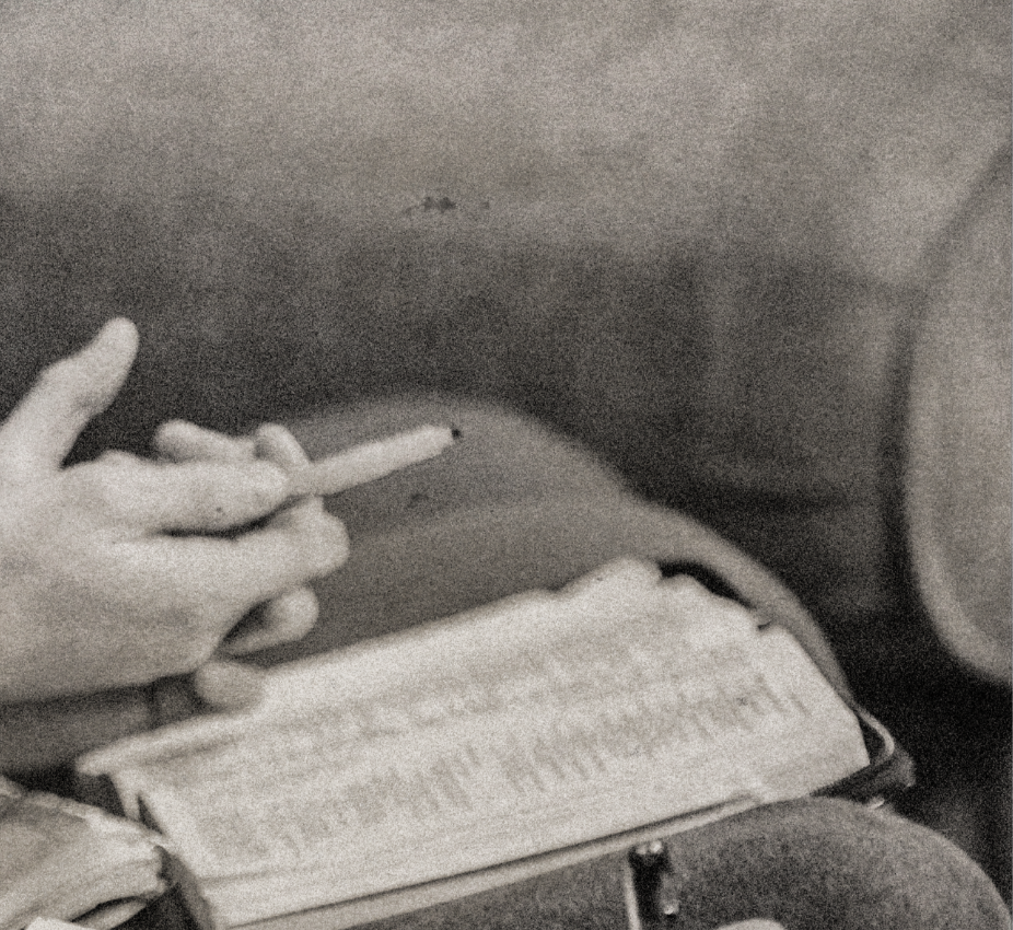 Person holding a pen while reading a notebook on a person's lap.