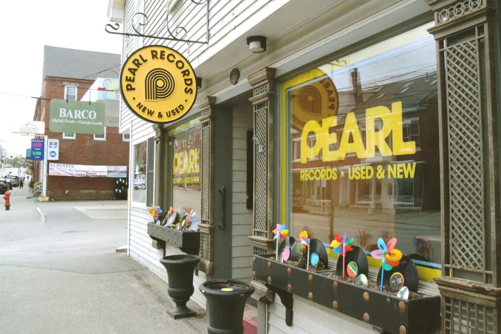 Storefront of Pearl Records displaying vinyl records with signage indicating they sell new and used records.