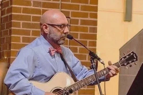 Dan-Mark Acoustic singing and playing guitar during a live performance.