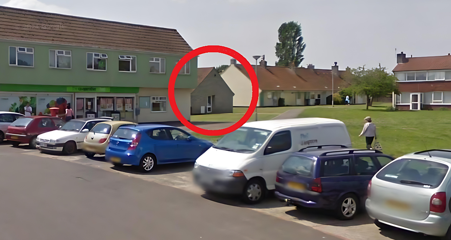 A small, old stone church building with a gabled roof, circled in red, in a suburban area with parked cars and people walking nearby.