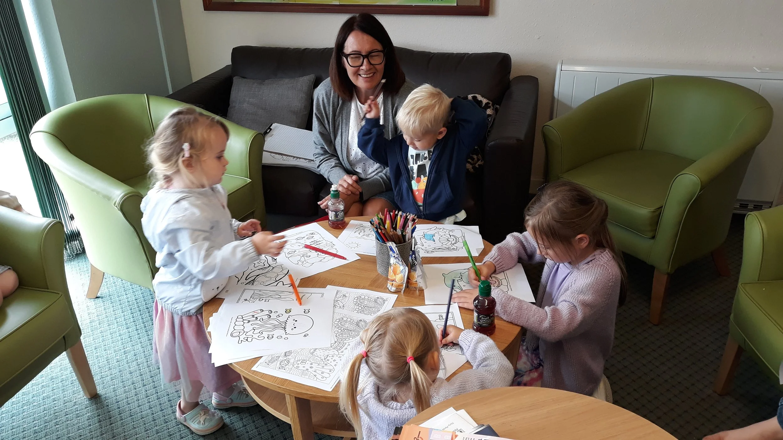 People spray-paint graffiti on a large wall at an outdoor art event. A van with Aerosol Art company branding is parked nearby, displaying paint supplies and a contact number.