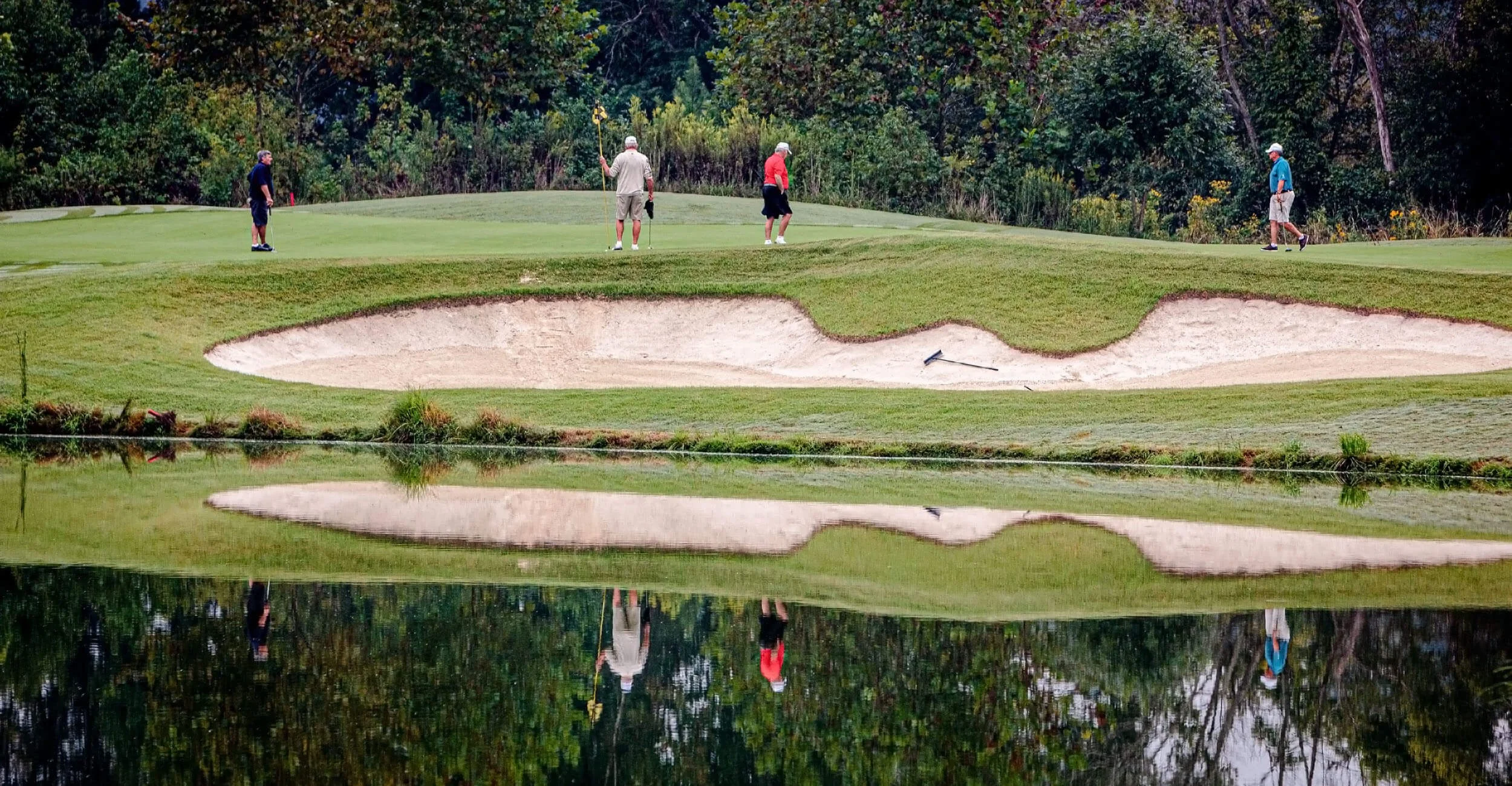 Four golfers standing on a golf green near a sand bunker at Carolina Lakes golf club in Sun City.  