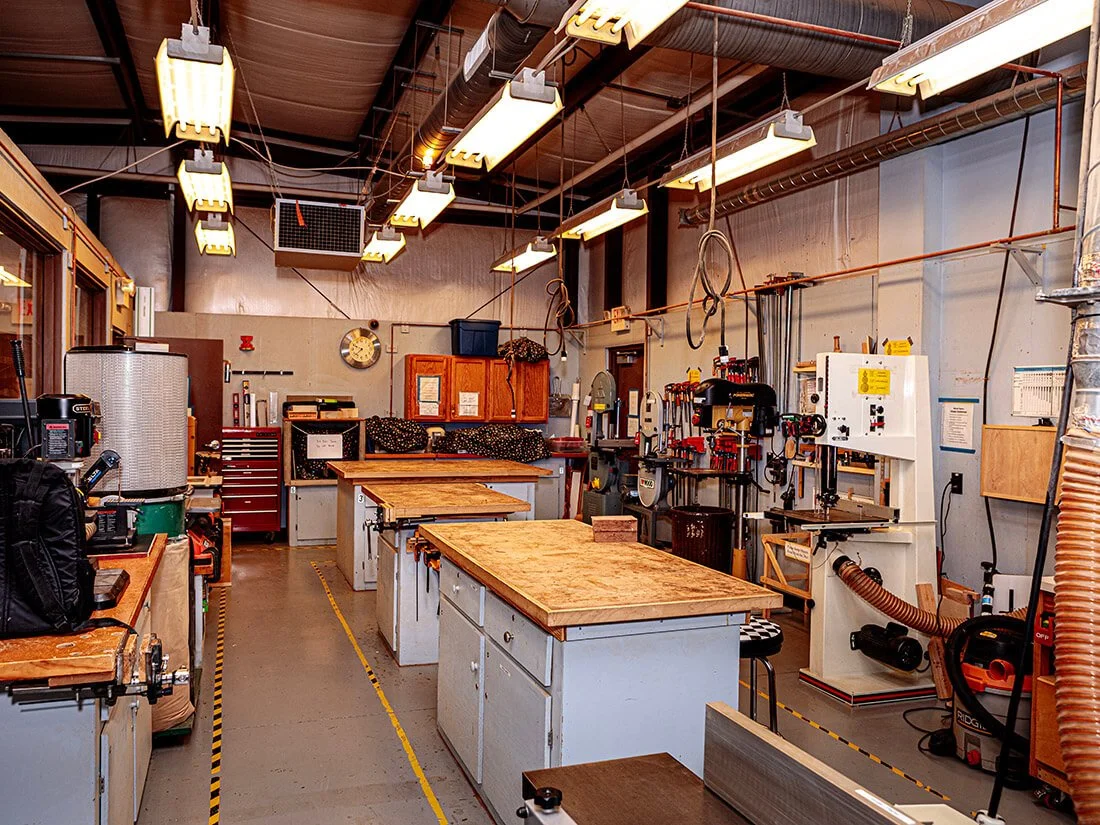 A well-organized woodworking workshop with workbenches, tools, and equipment.