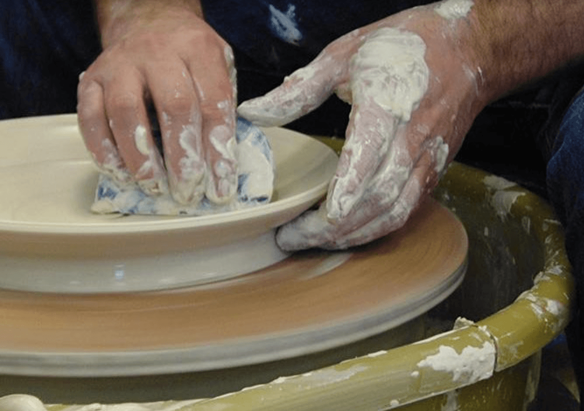 Hands shaping clay on a pottery wheel in a pottery studio.