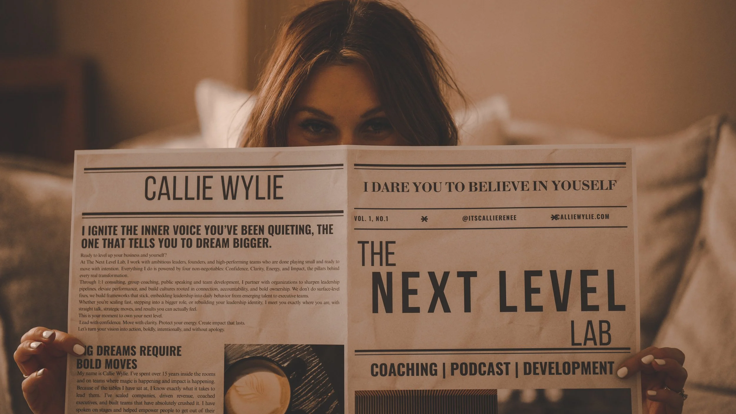 Woman with brown hair holding a newspaper titled 'The Next Level Lab', partially covering her face, in a cozy indoor setting.