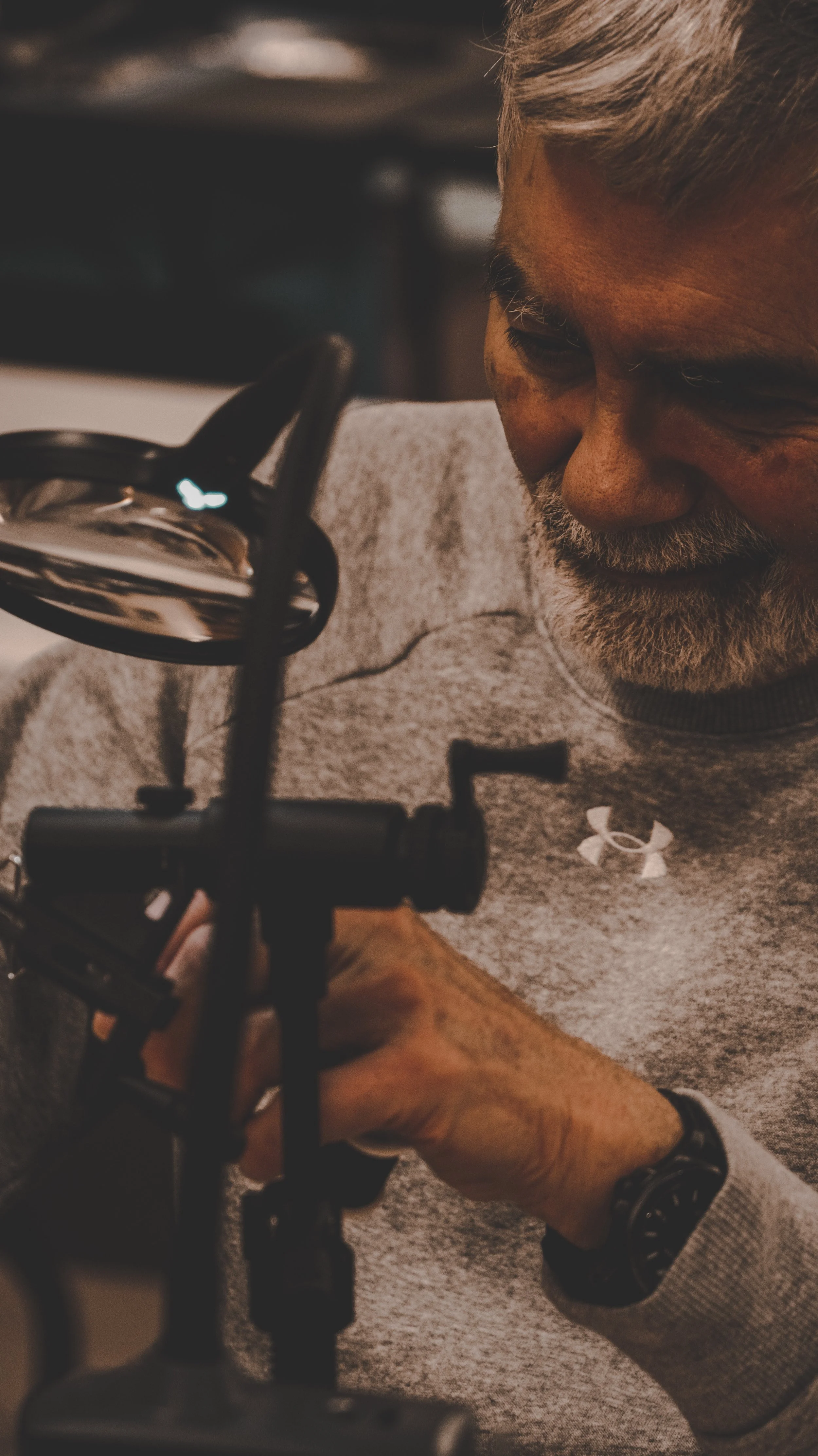 A man with gray hair and a beard smiles as he adjusts a piece of photography or filming equipment.