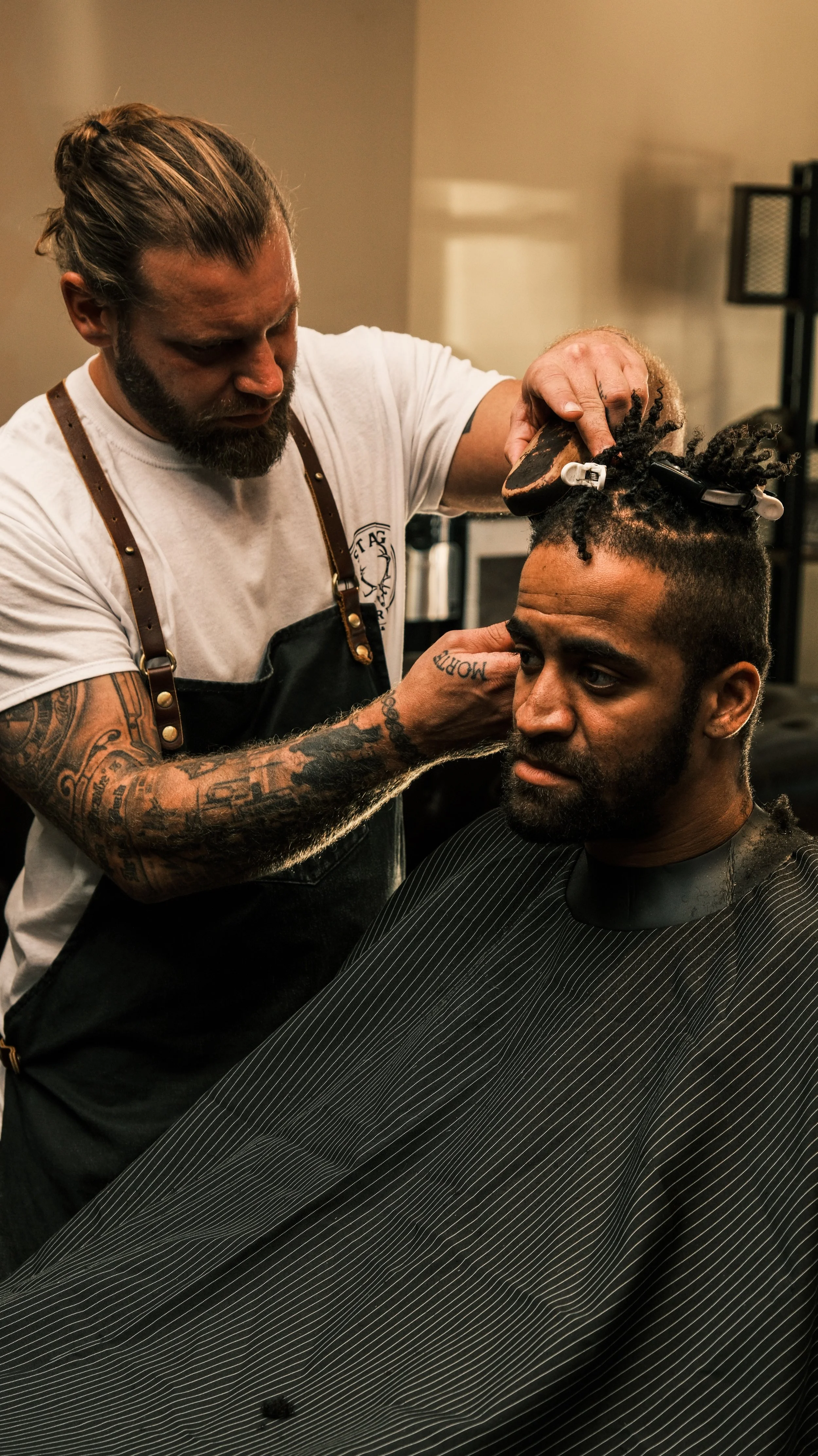 A barber cutting a man's hair in a barbershop.