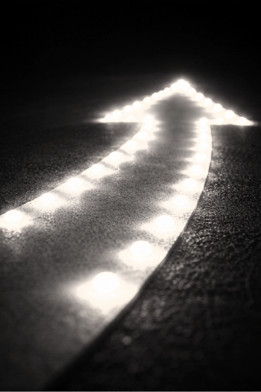 A luminous arrow on the ground pointing forward, illuminated by bright LED lights at night.