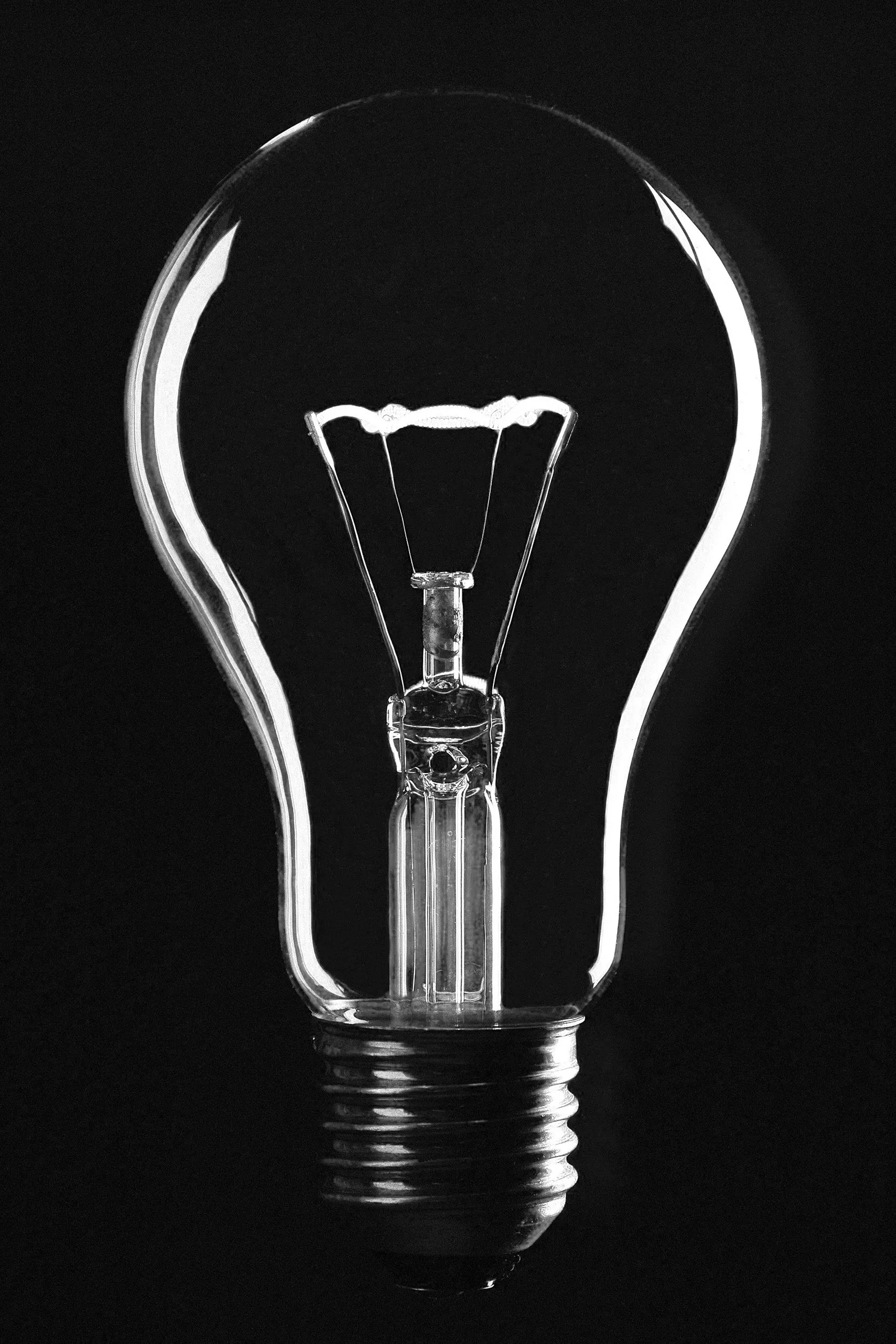 Close-up of a glowing incandescent light bulb against a black background.