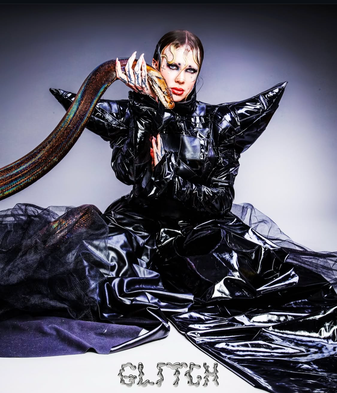 Futuristic fashion styling: Model in a high-shine black ensemble illustrating a snake for a conceptual shoot.