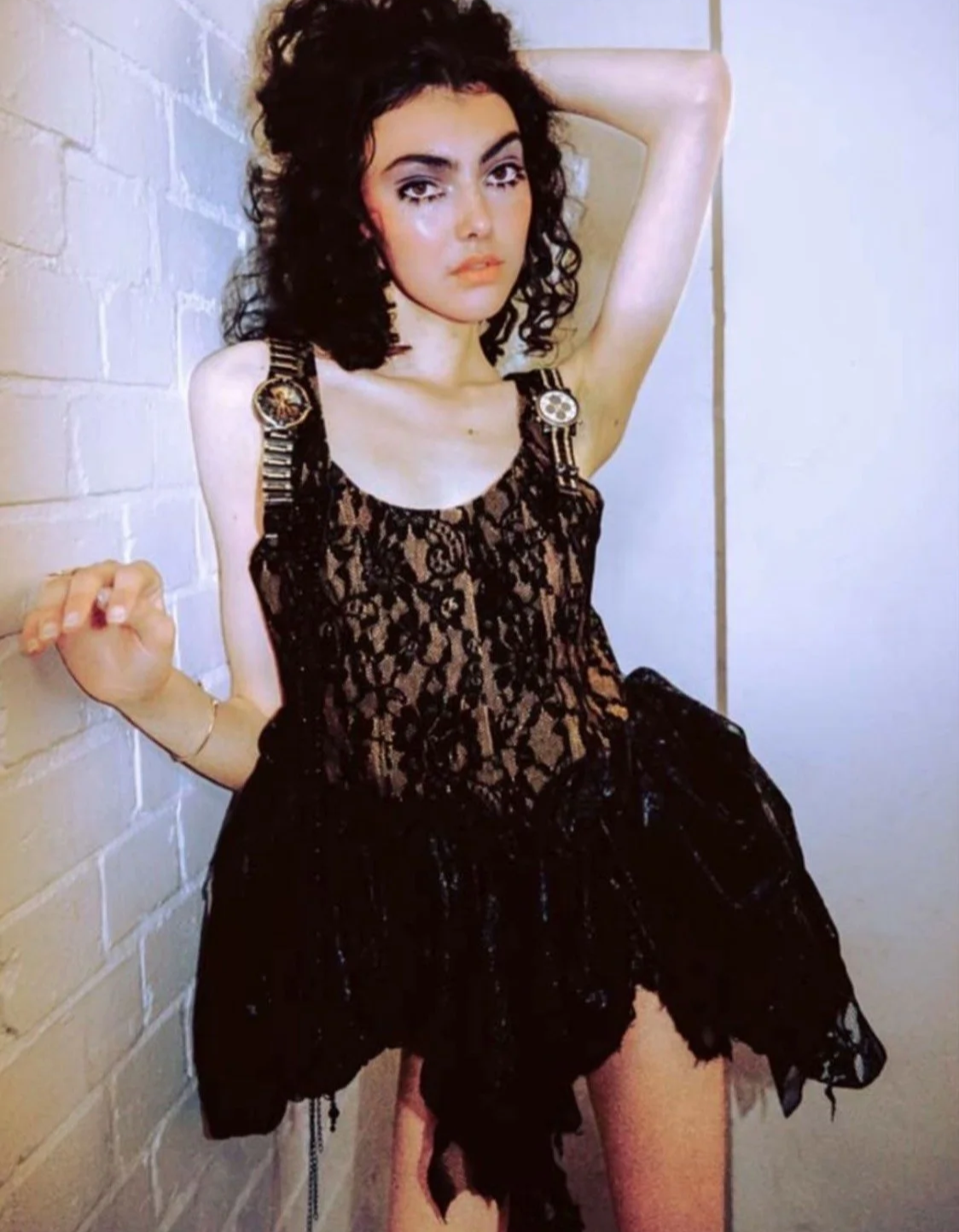 Contemporary styling: Architectural black lace dress with decorative straps and sheer elements, highlighting silhouette and texture.