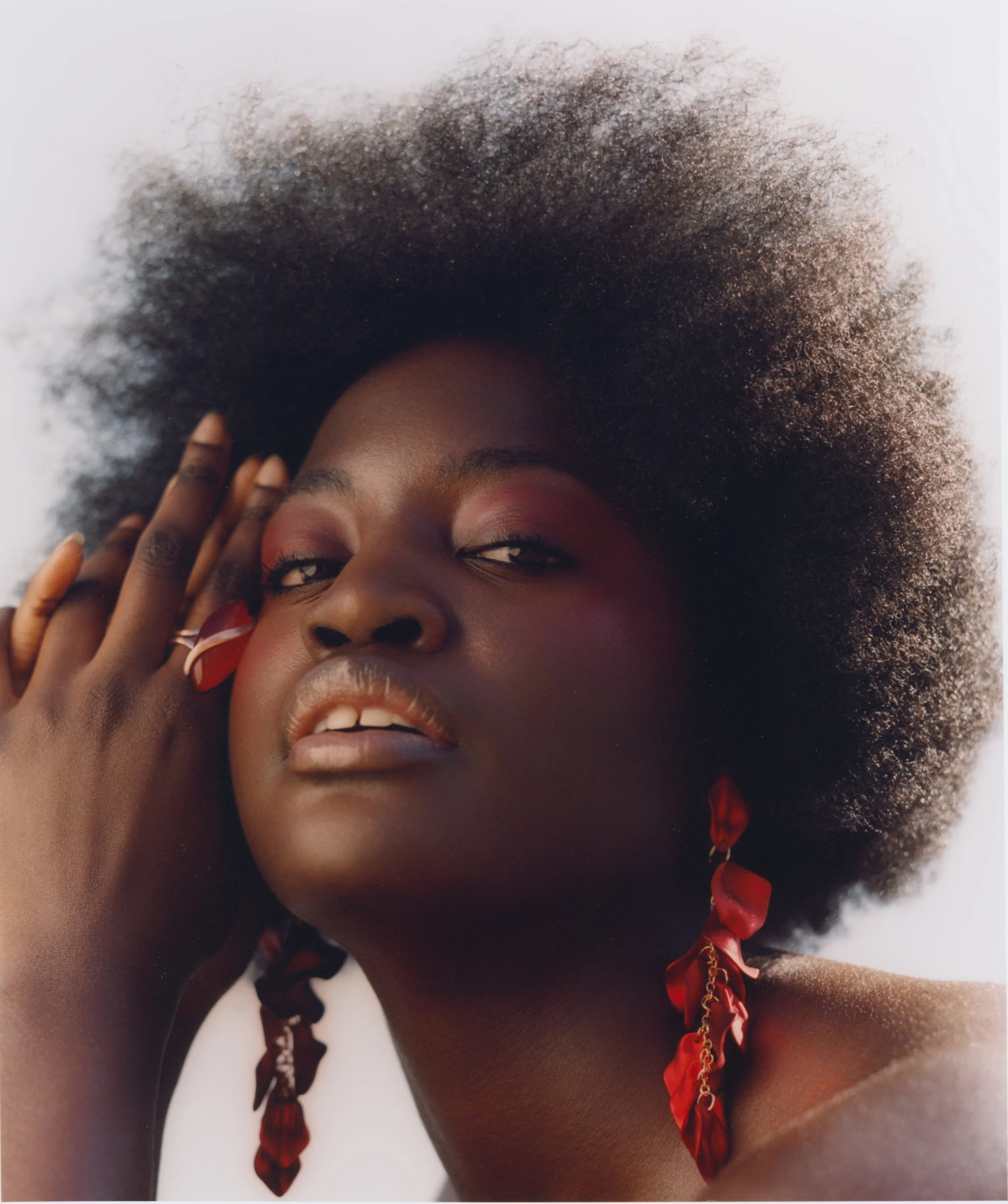 Natural light beauty portrait: Focus on ethereal pink makeup and bold red accessories, utilising soft daylight to enhance the color palette.