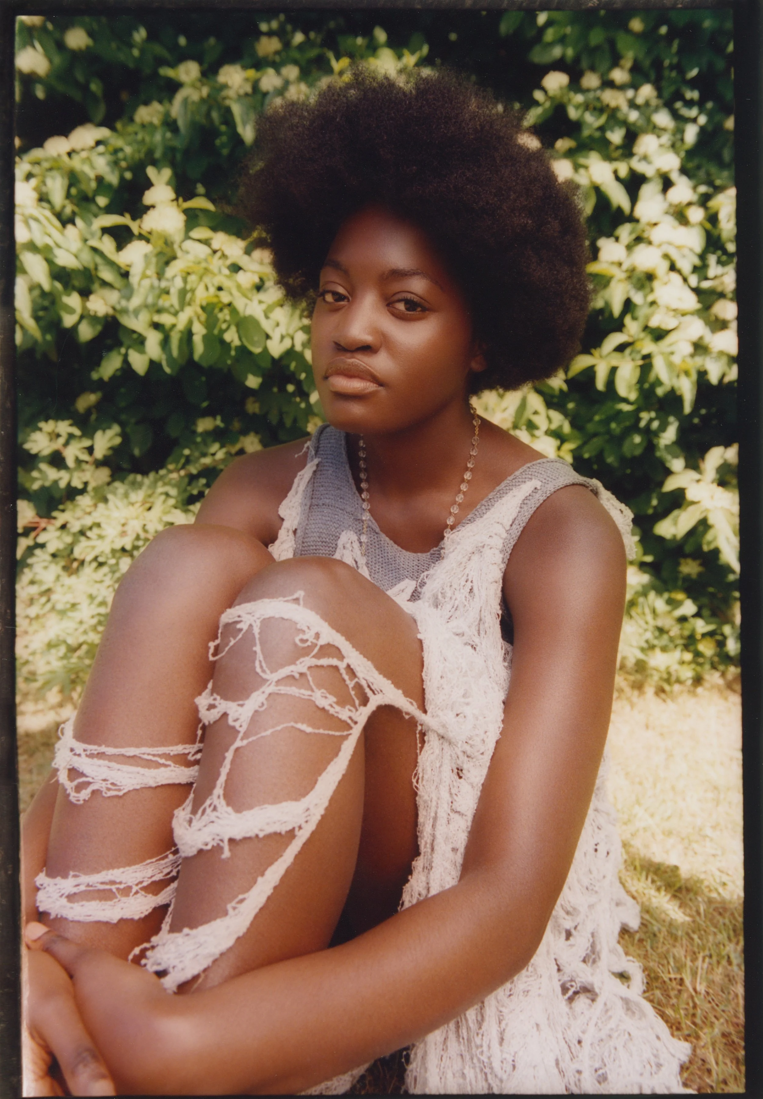 Textural fashion study: Model in a distressed lace ensemble and beaded accessories, illustrating a relaxed, organic outdoor narrative.