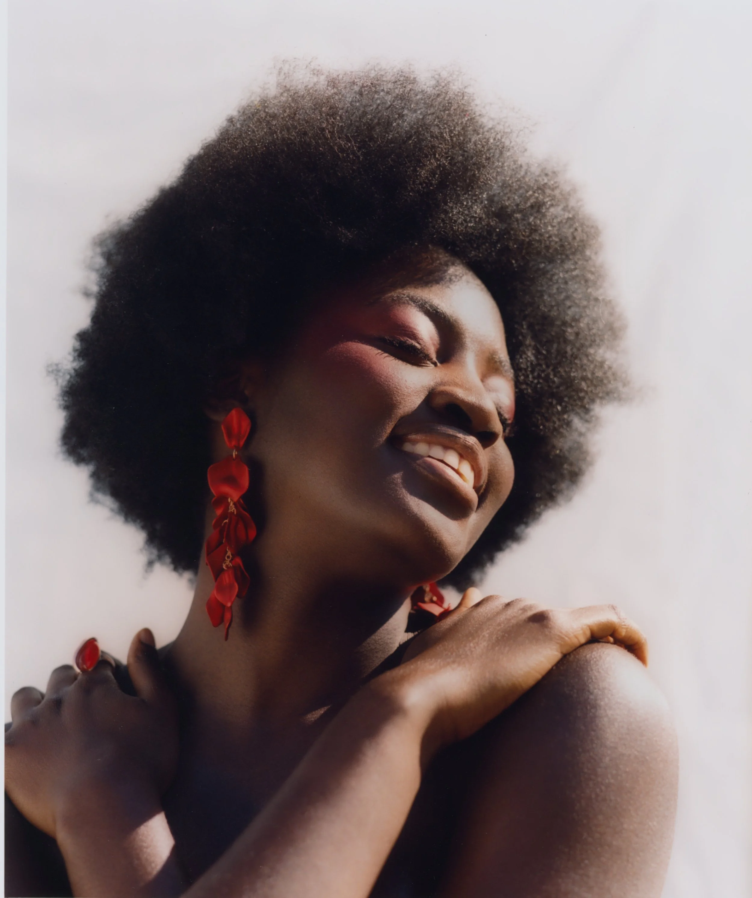 Vibrant location portrait: High-key styling featuring bold red jewelry and a minimalist background, emphasizing warmth and saturated color.