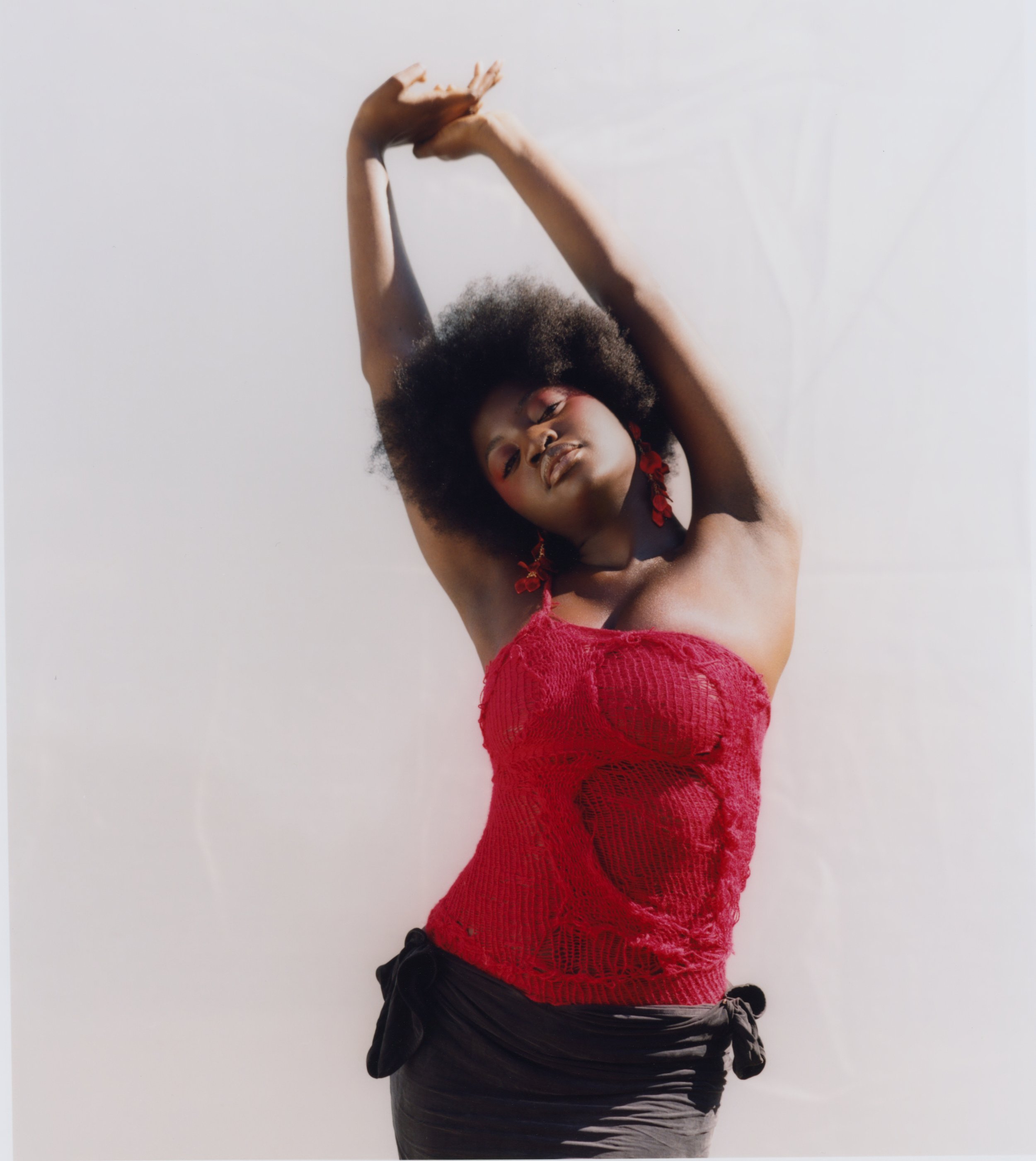 Expressive movement styling: Red lace textures captured against a high-key natural background.