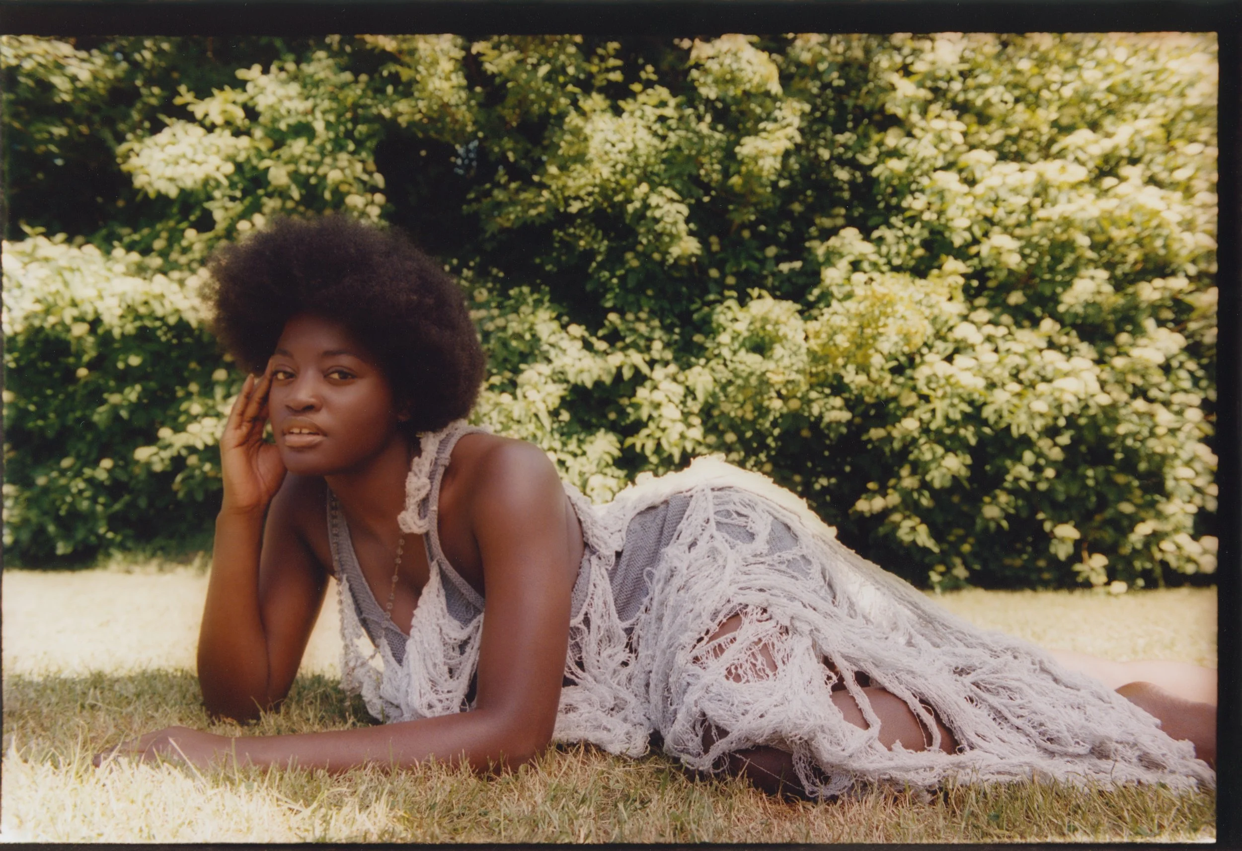 Botanical fashion story: Model in a deconstructed, light-toned dress illustrating soft textural contrast against a natural floral backdrop.