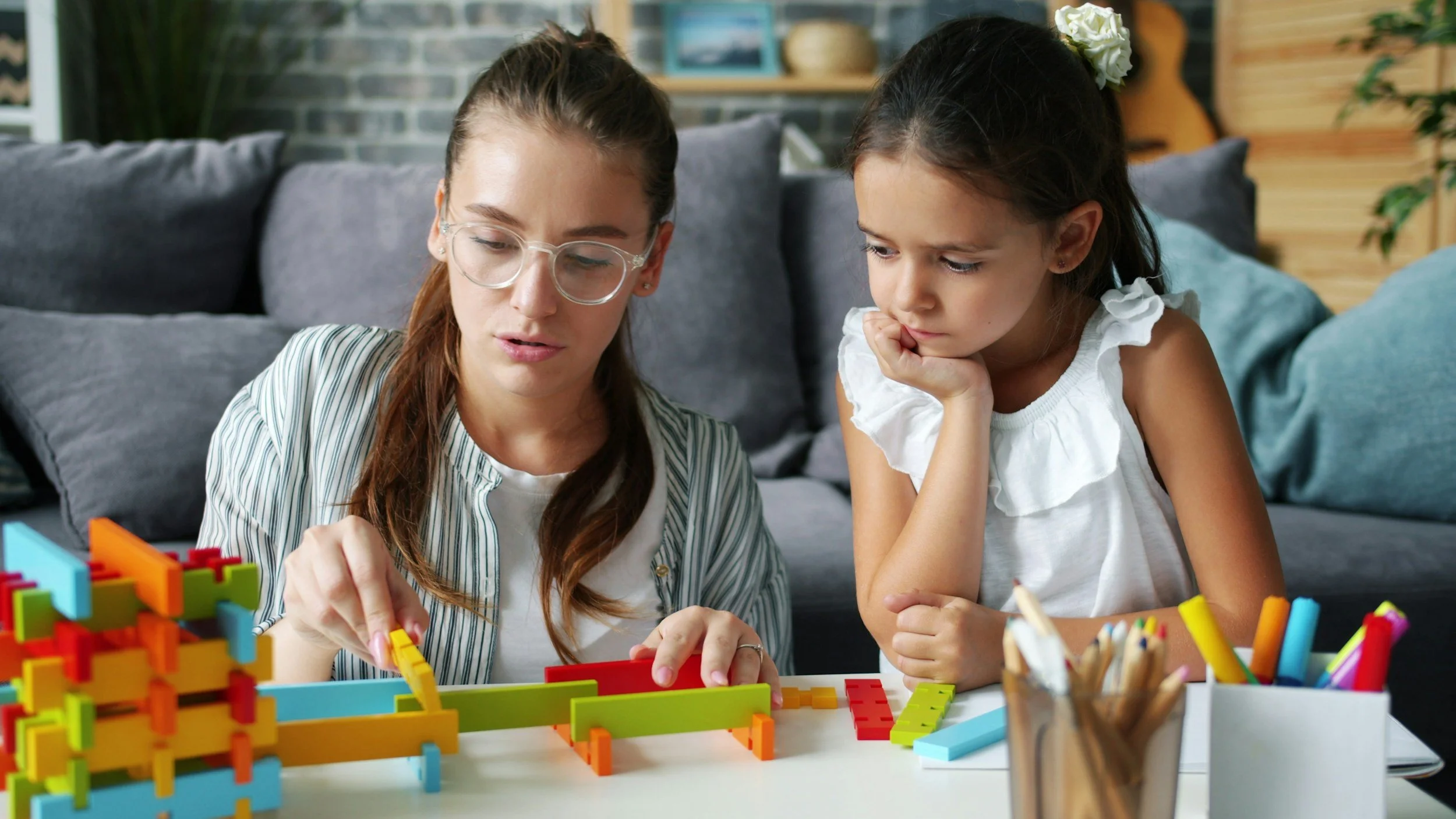 Adult and child building together with geometric blocks during an ABA therapy session