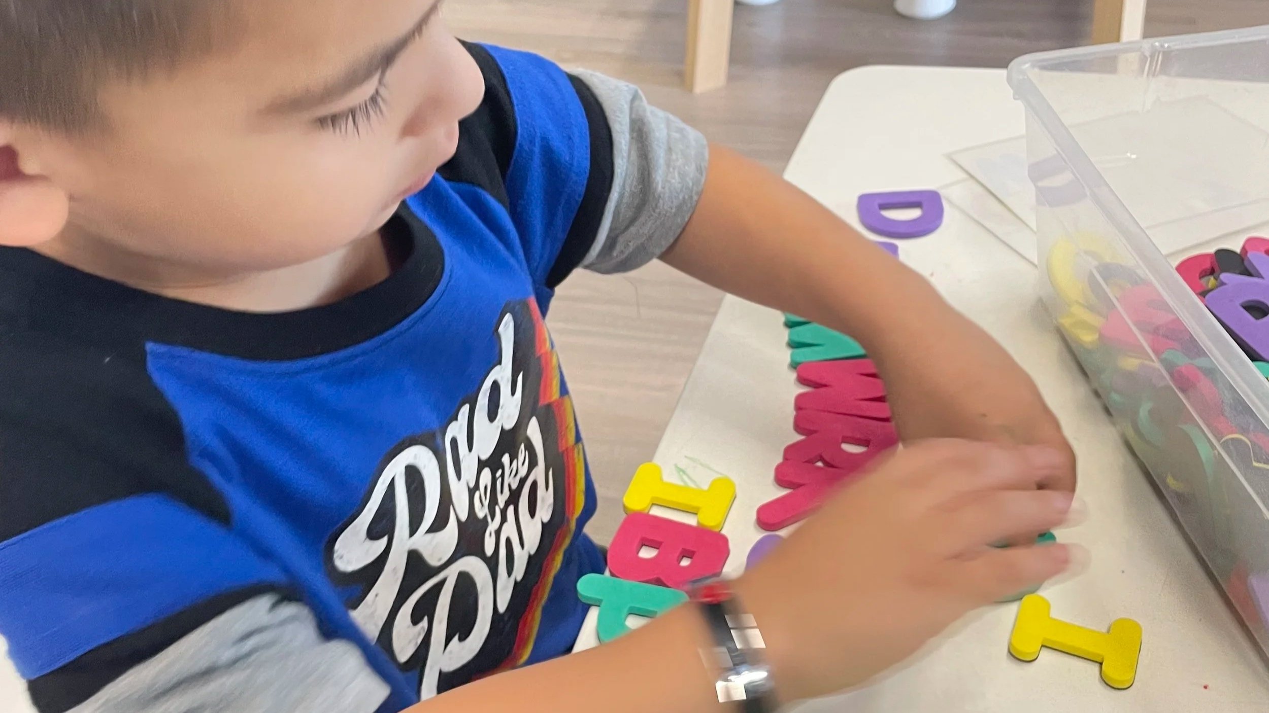 Child lining up letter puzzle pieces, as play during observation