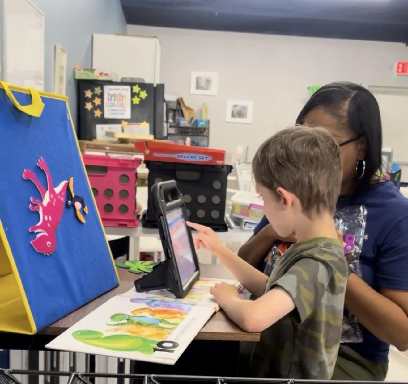 Speech therapist is working with a child on using an AAC device