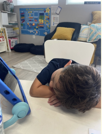 A child has his head down on top of his folded arms taking a break