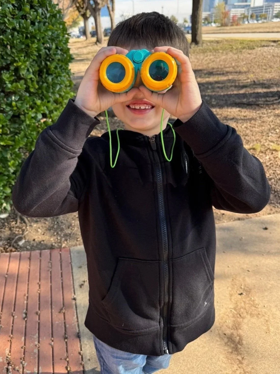 Child looking through toy binoculars during an ABA therapy play activity