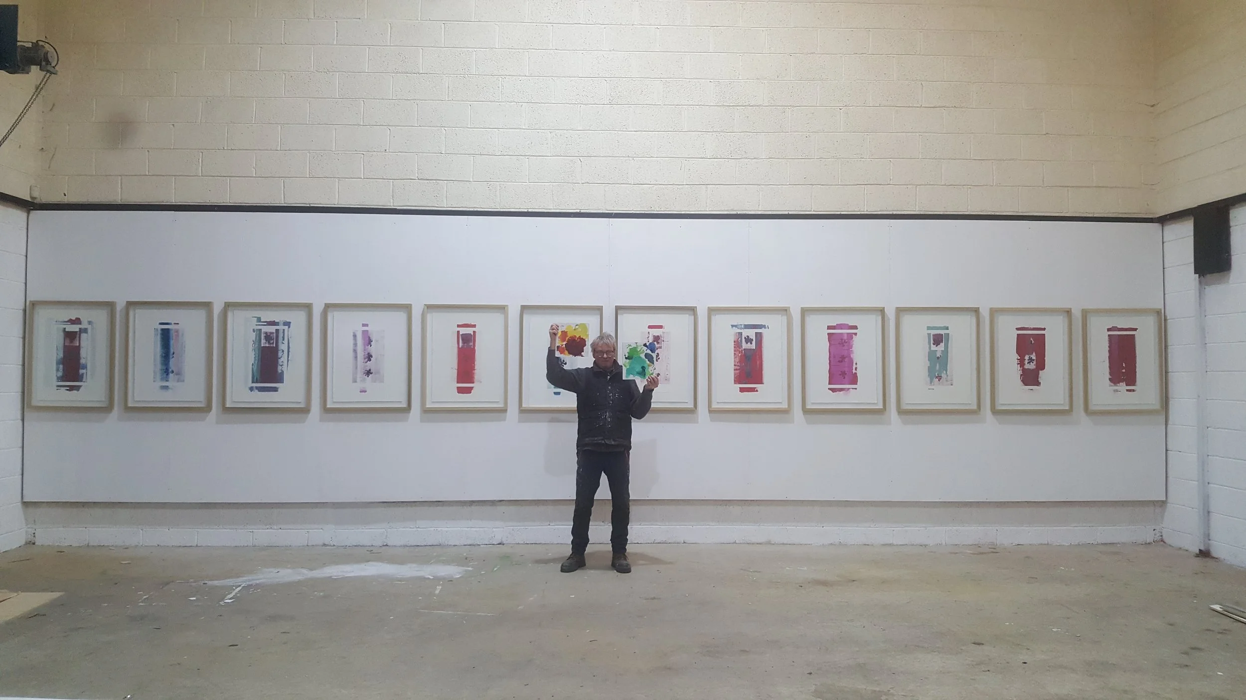 The artist standing in his studio with the series of artworks entitled "The Fall" from 2020.