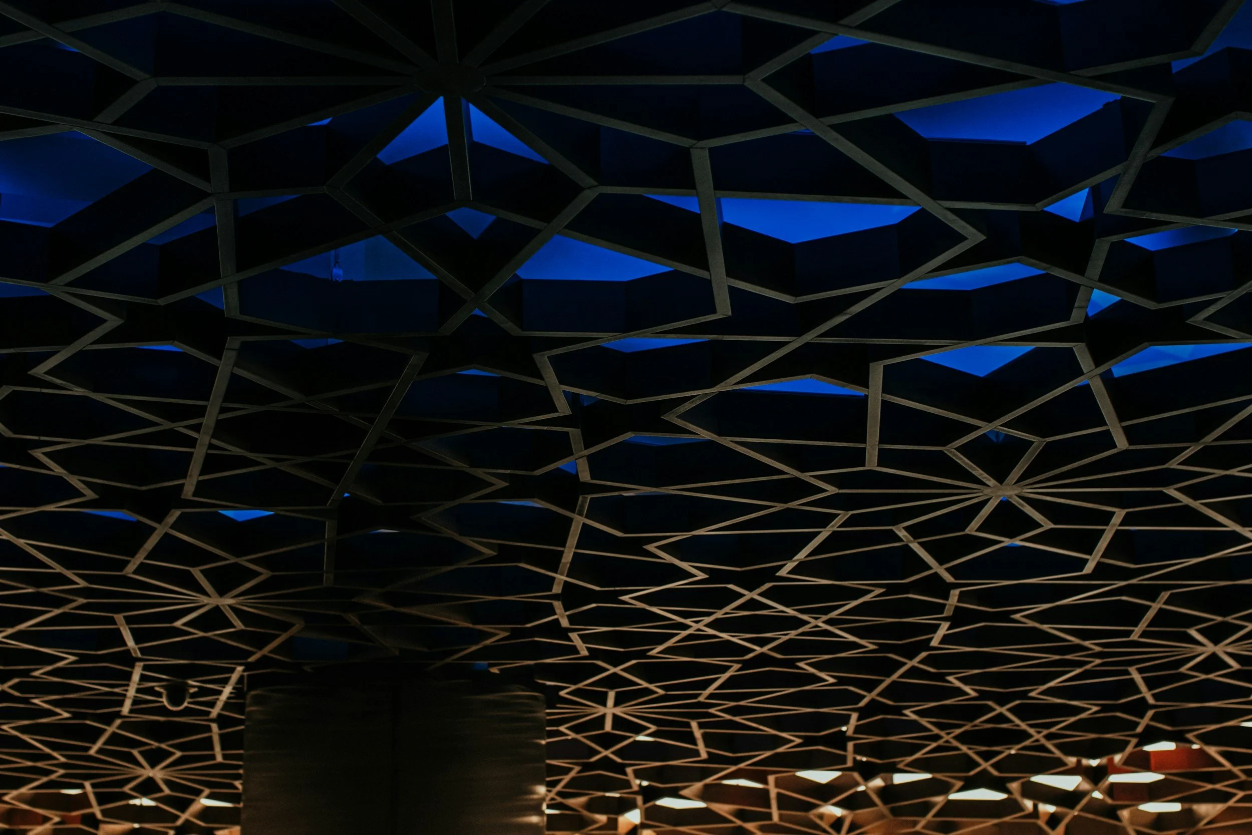 Geometric decorative roof structure with blue and orange lighting, reflecting structure and design