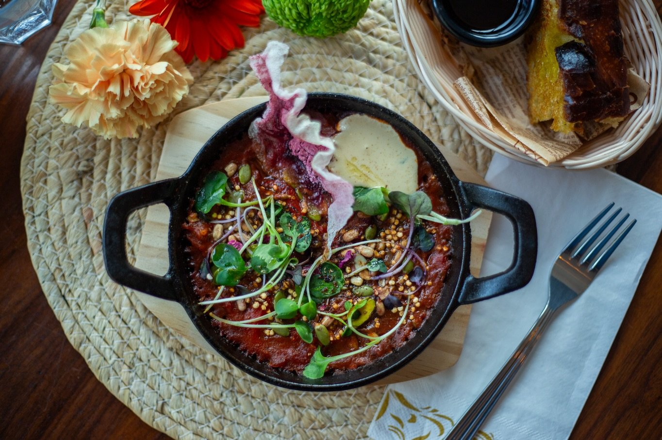 Notre shakshuka (V&eacute;g&eacute;talien) est compos&eacute;e de tomates mijot&eacute;es, de poivrons rouges grill&eacute;s et de l&eacute;gumes d&rsquo;hiver, le tout agr&eacute;ment&eacute; de tahini, de micro-radis et d&rsquo;herbes aromatiques.
