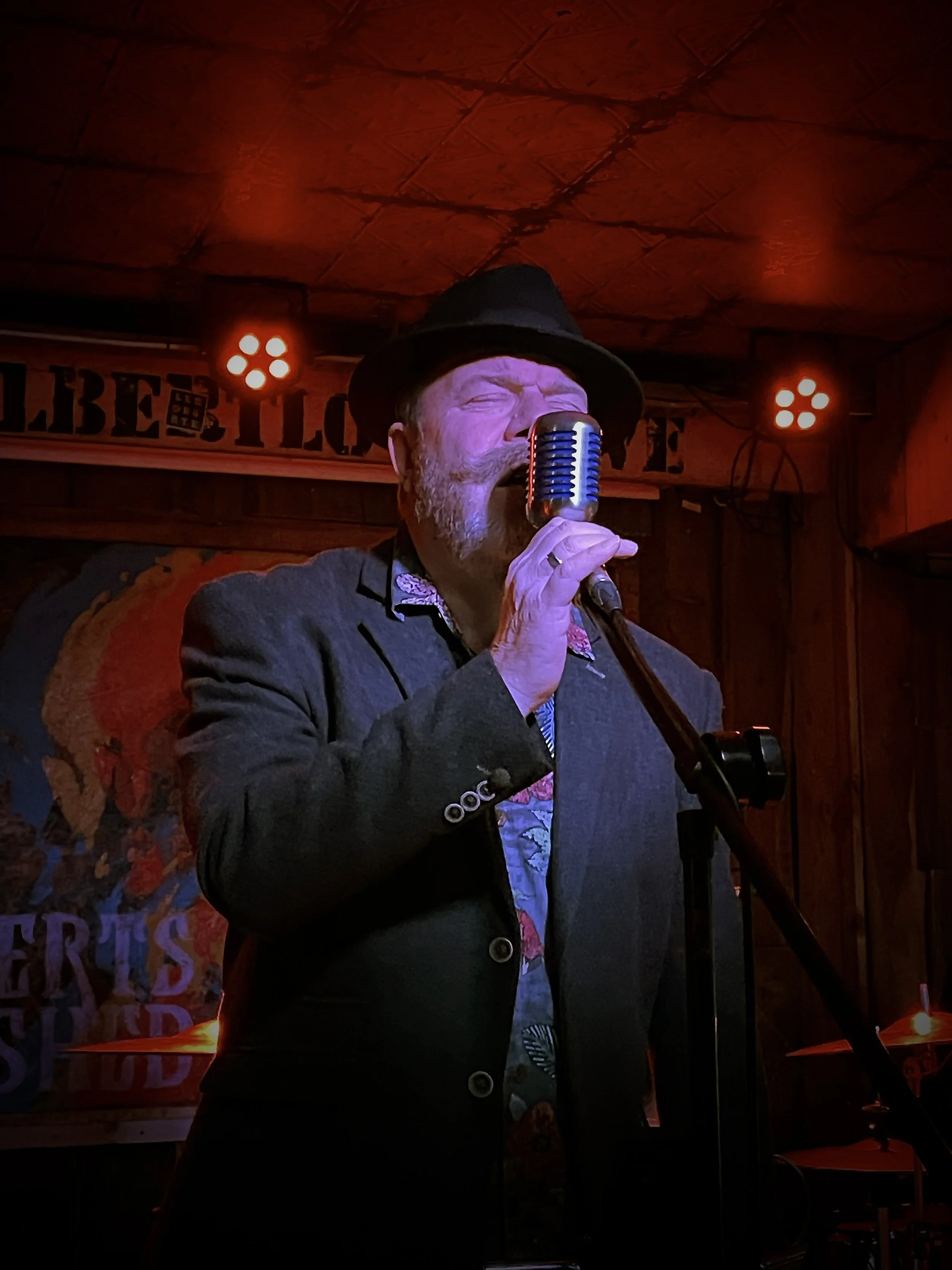 Mr G singing under red lights.