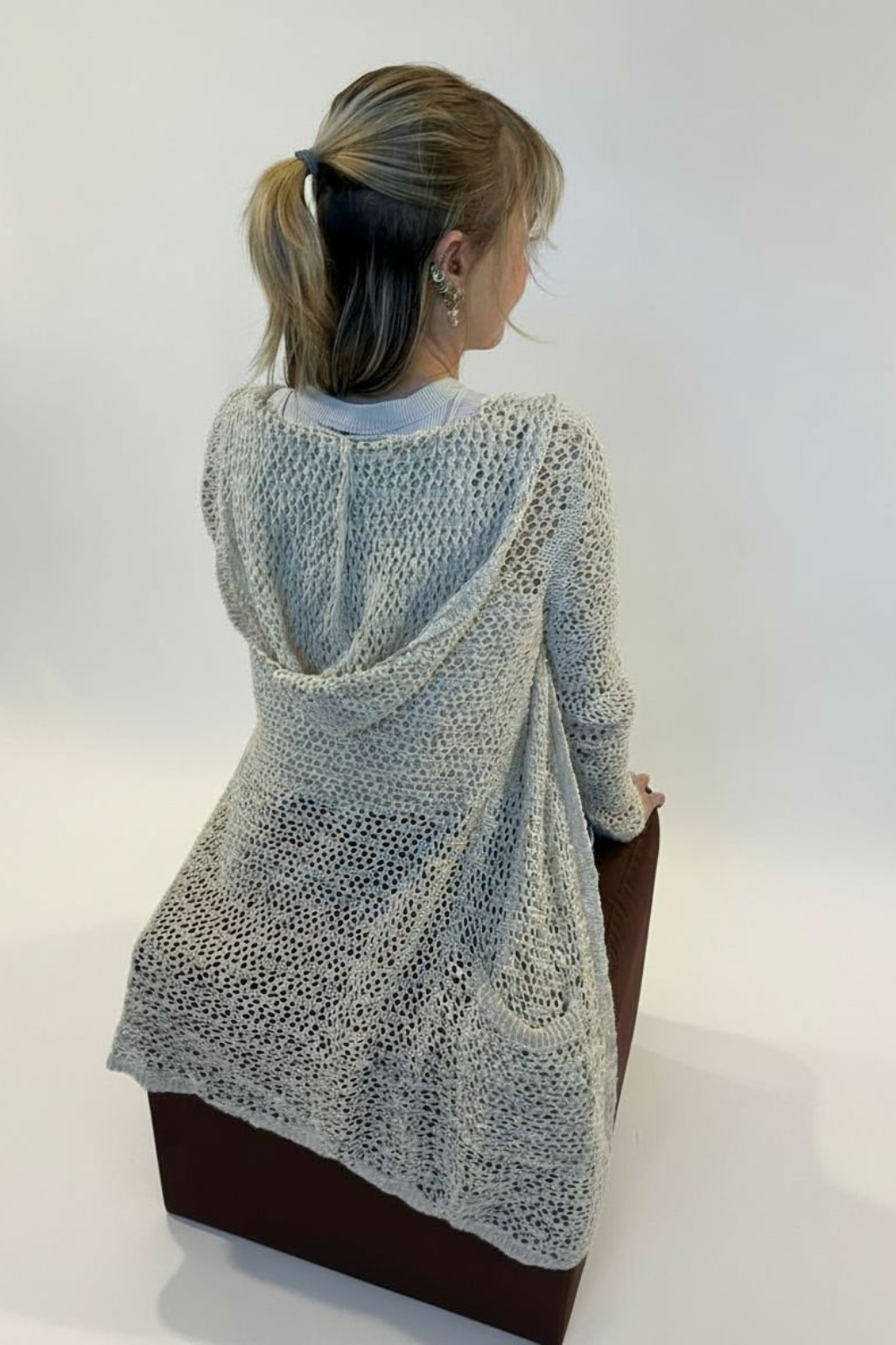 Fair-Skinned Woman With Blonde Ponytail Seated On Ottoman.png