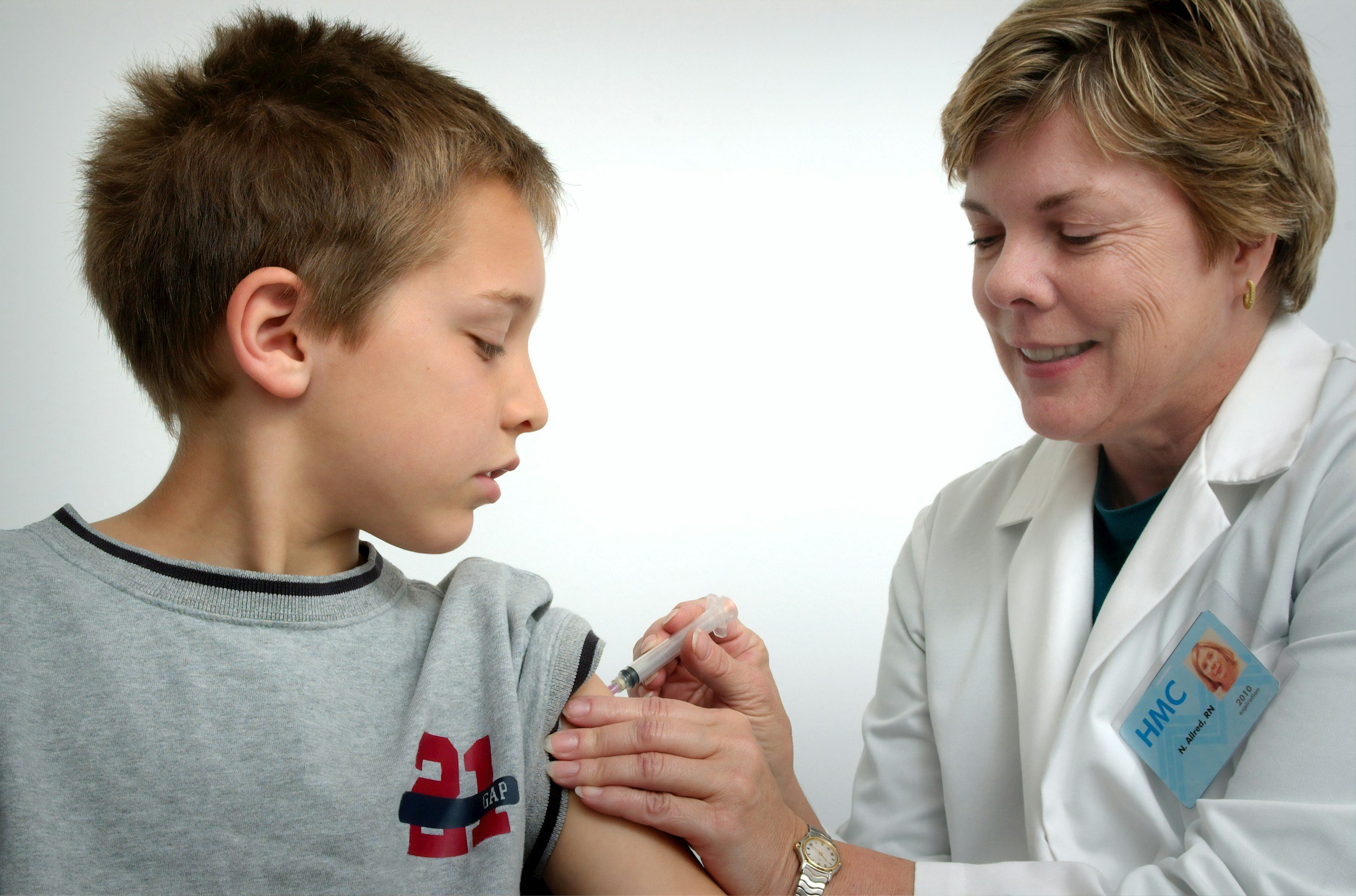 A nurse administering a vaccination to a young boy in a clinical setting.