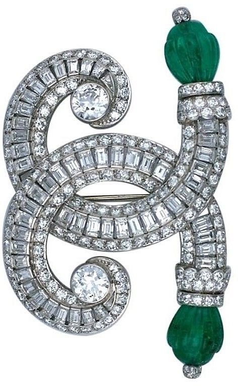 Broche ornementale en forme de spirale ornée de diamants et de pierres vertes.