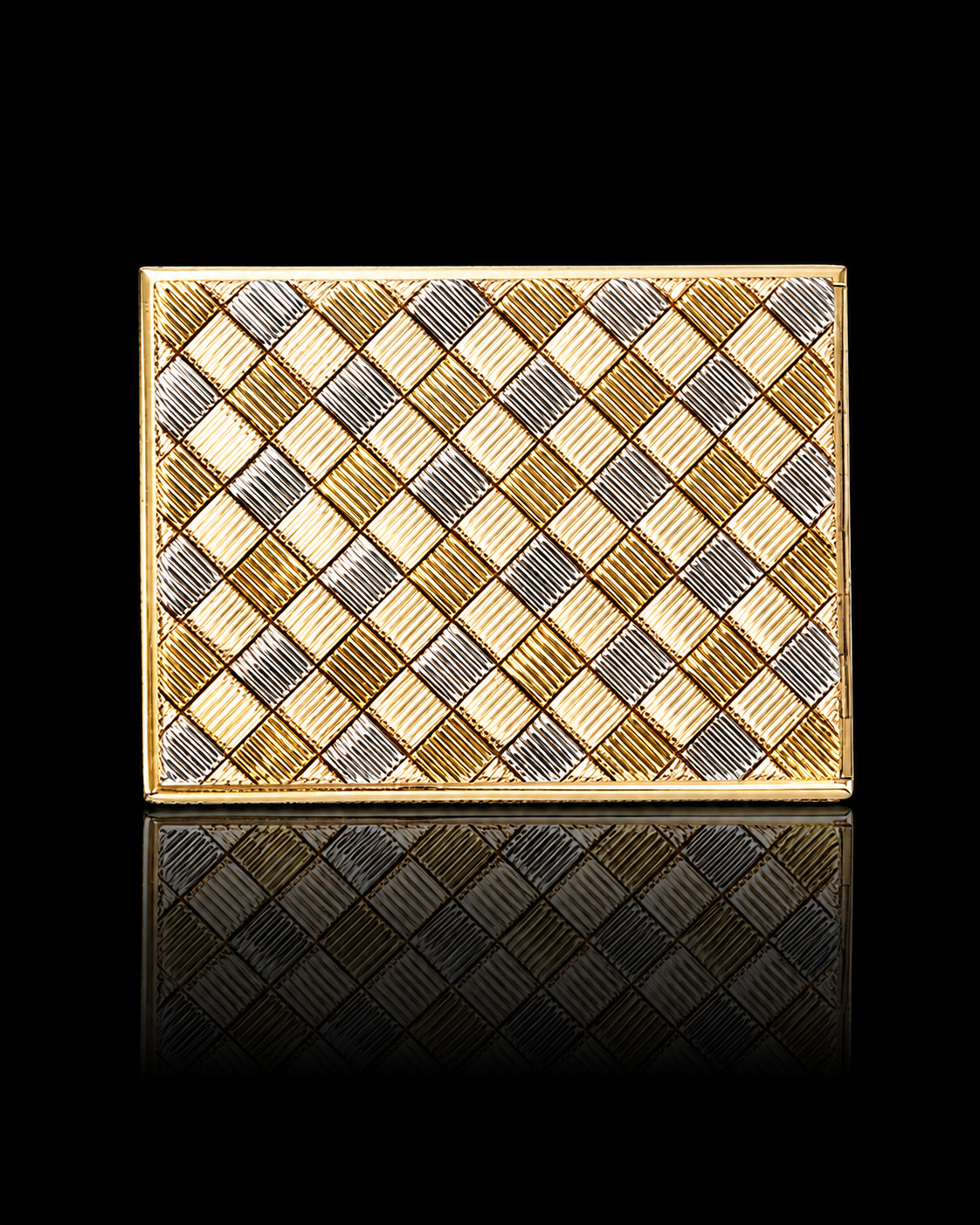 Une boîte décorative en or et argent avec un motif en forme de carré sur un fond noir, et une reflection en dessous.