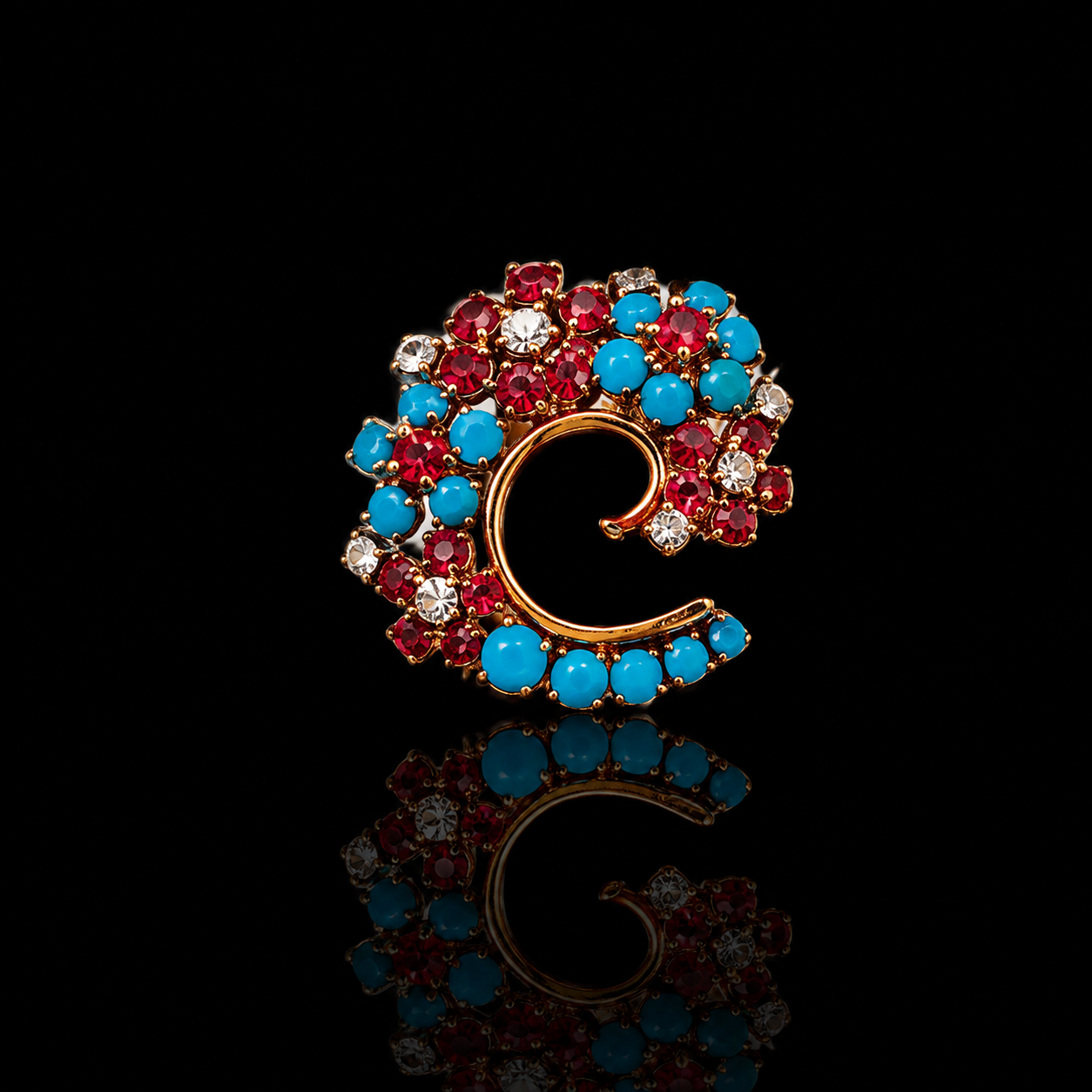 Broche en forme de lettre C ornée de perles bleues, rouges et claires avec fond noir