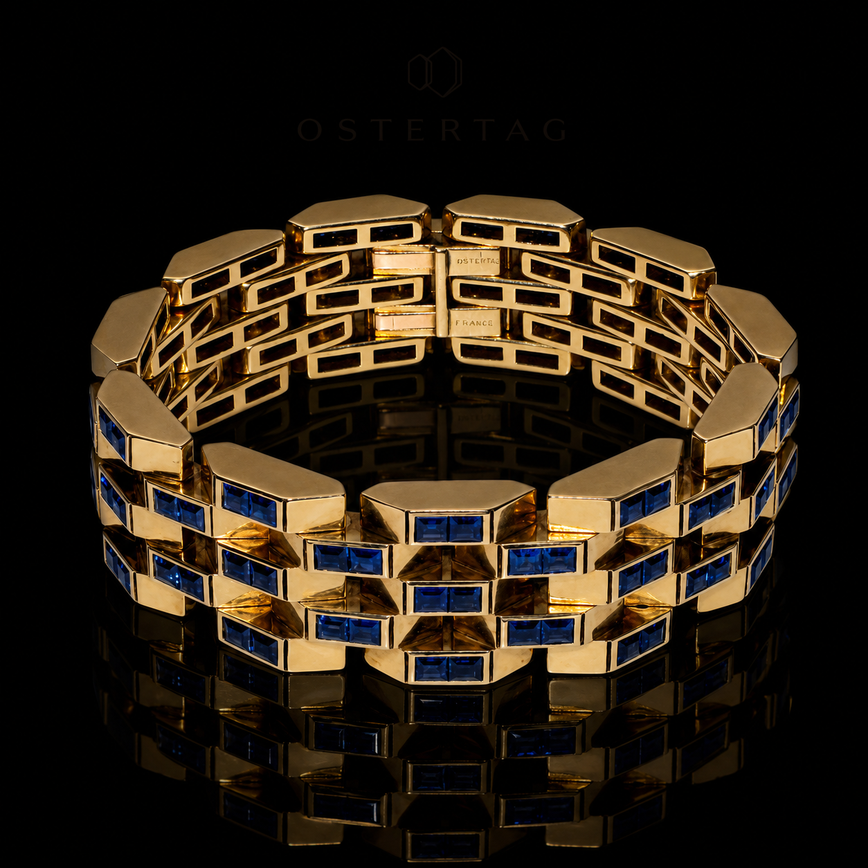 Bracelet en or avec des pierres bleues, posé sur un fond noir avec reflet