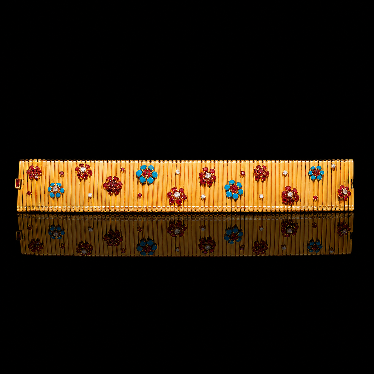 Une broche en or ornée de fleurs en émail rouge et bleu, avec des pierres précieuses.