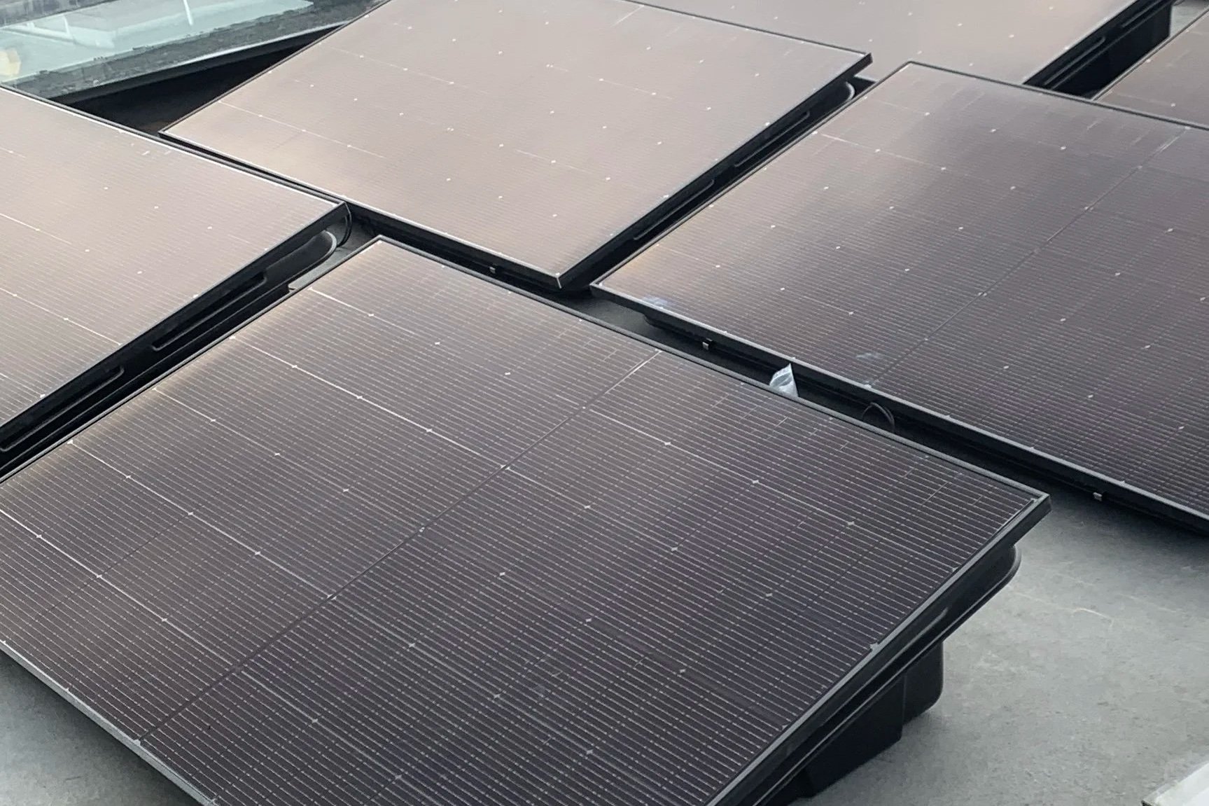 Several solar panels laid out on a flat surface on a high rise building installed by specialist steeplejack and access contractors.