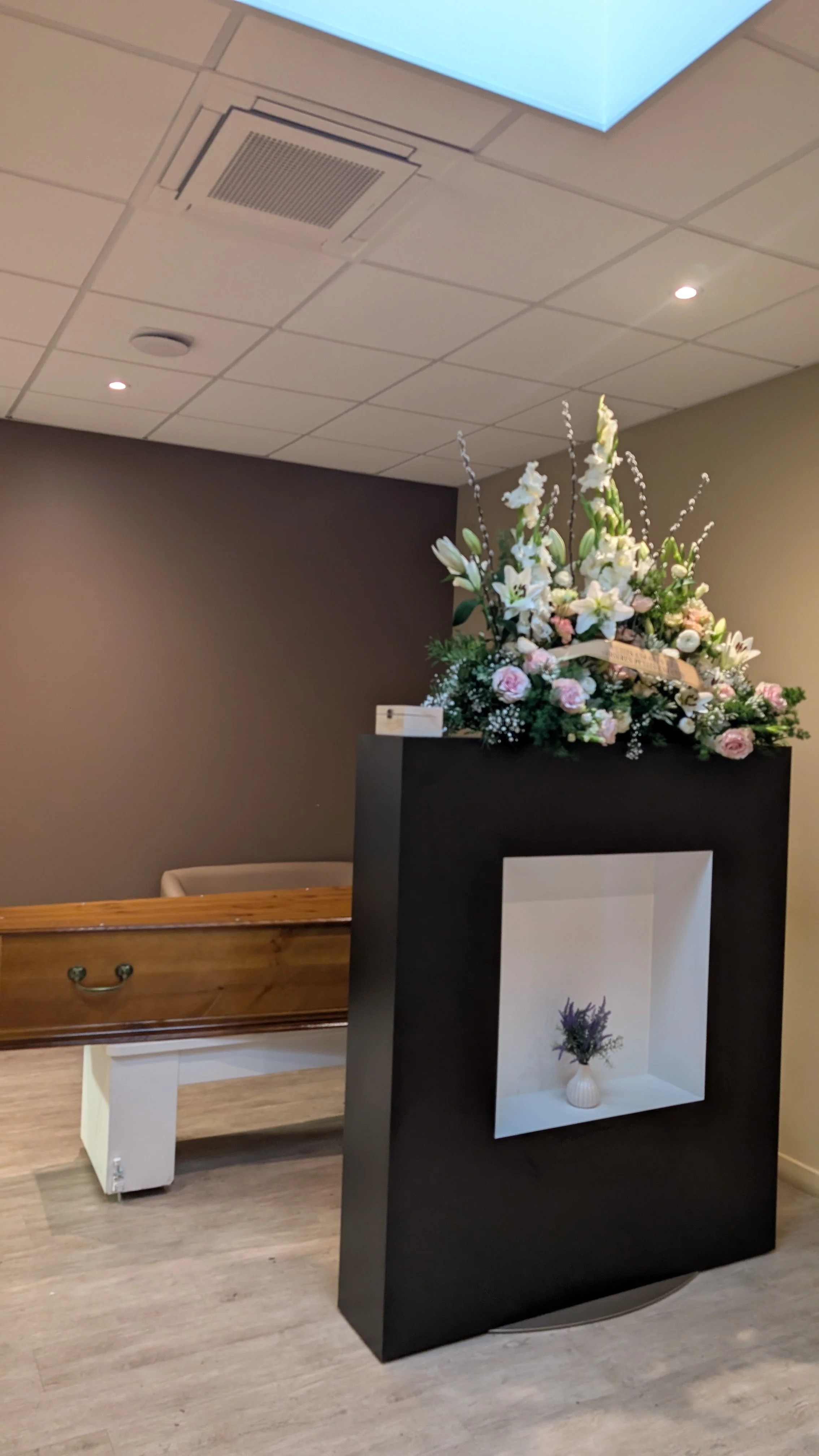 Une décoration florale composée de fleurs blanches et roses dans un salon funéraire