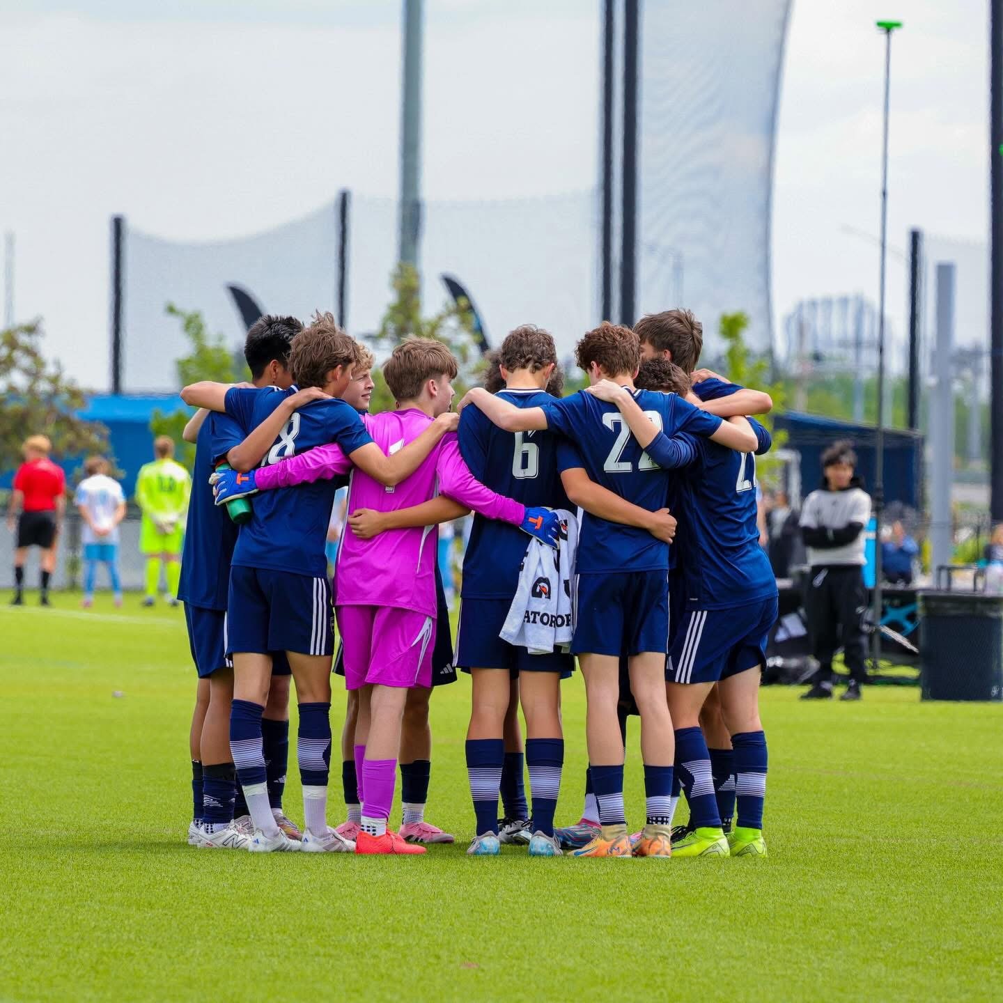 Soccer team huddled together on the field before a match