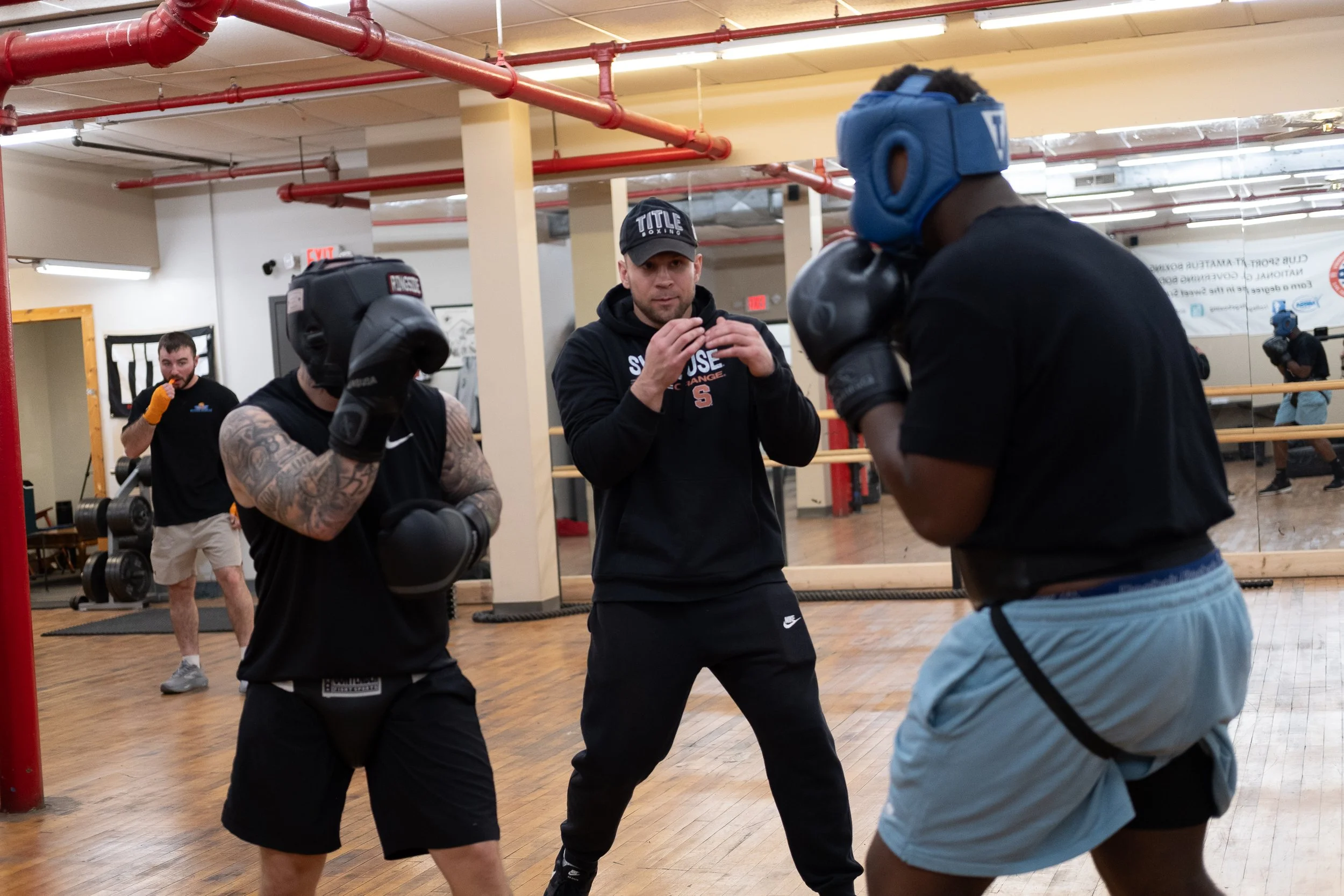  Coach Joe Stray (middle) instructs Ryan Fogarty (left) and Jamere Smith (right) during a sparring practice match. Photo by Rabia Mustafa.  