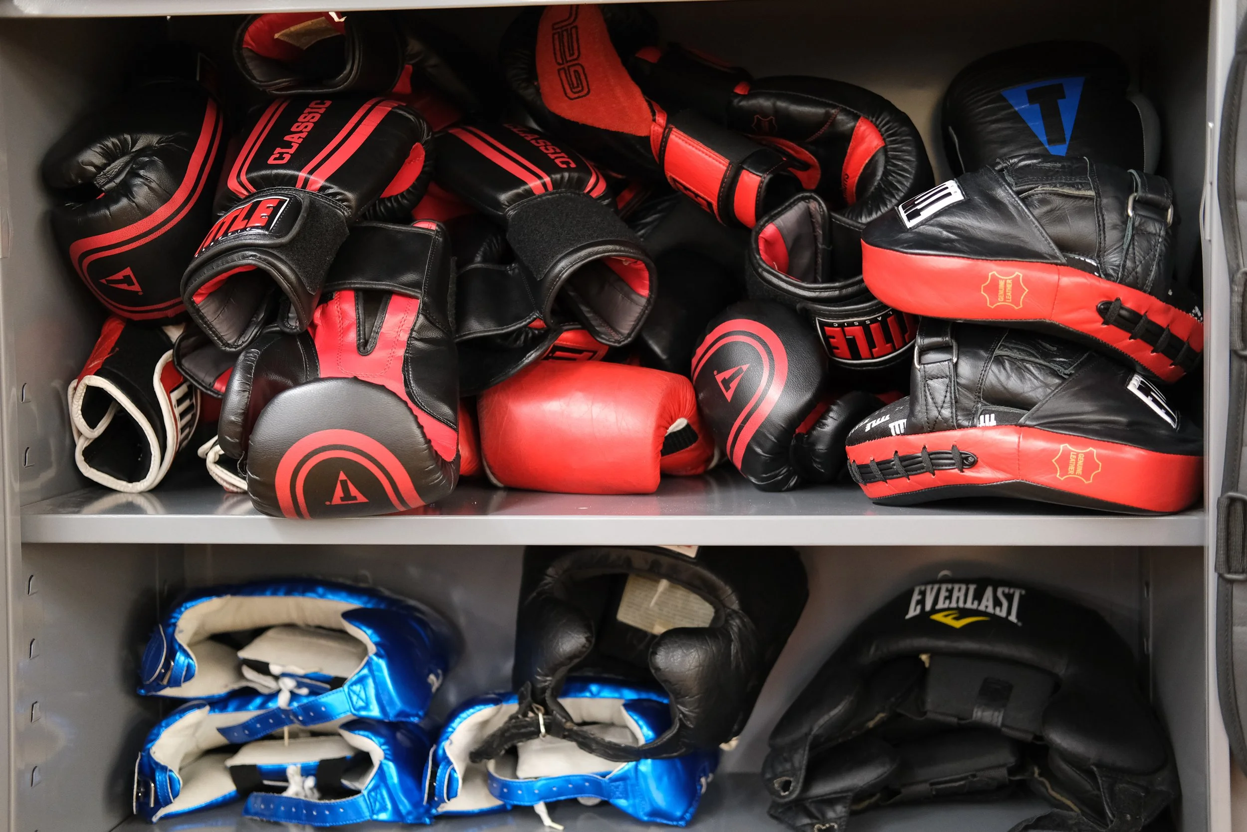  Red boxing gloves and blue headgear inside a gym closet, ready to be used by the next students. Photo by Jirah Johnson. 