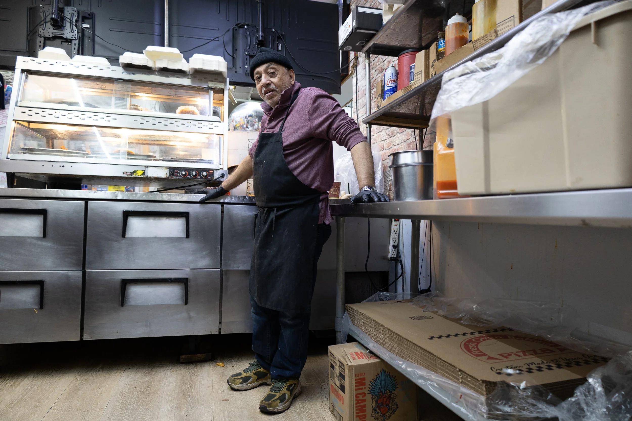  Ahmed, known to regulars as "Uncle Ahmed" or "Pops," pauses from cooking in the hot food prep station at Ze Mart on Jan. 10, 2026. Photo by: Destinyi Fernandez 