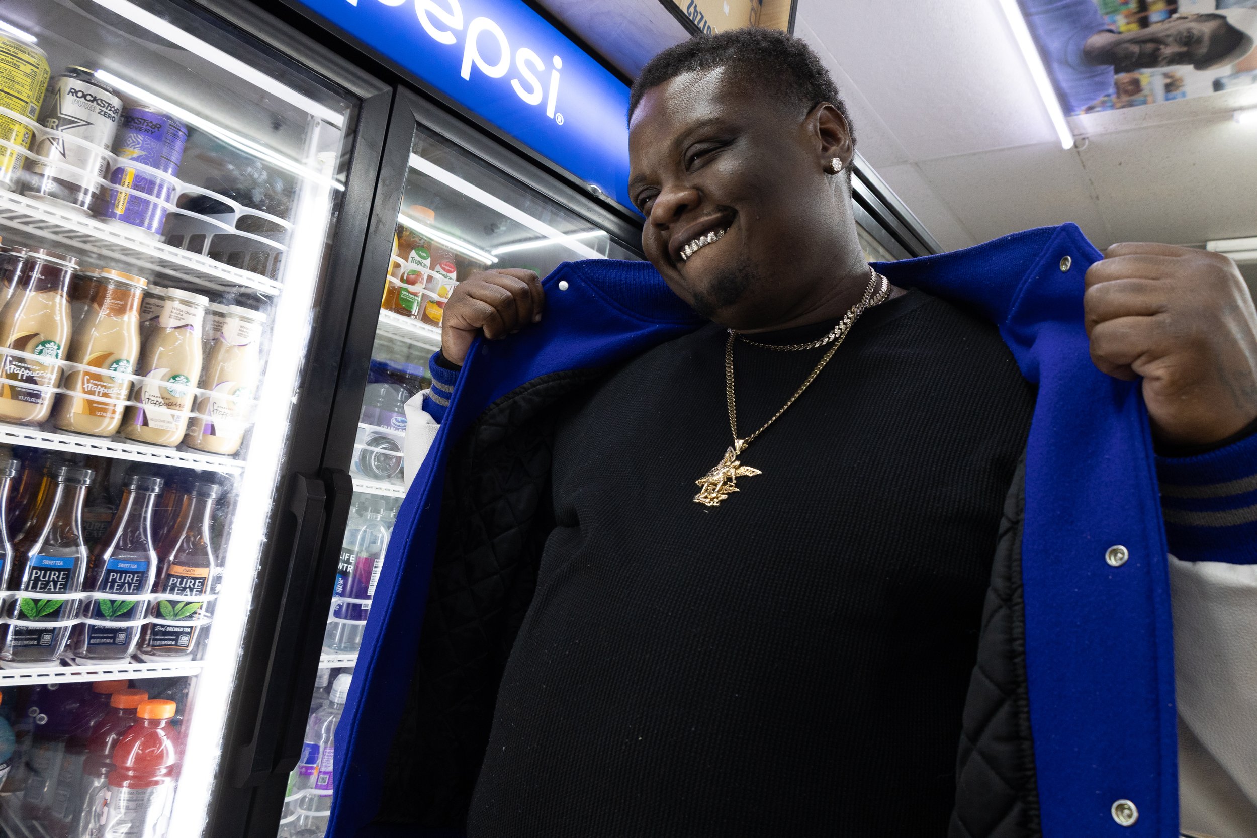  A man poses in front of a Pepsi cooler inside Ze Mart, opening his jacket to show a chain and shirt underneath, on Jan. 17, 2026. Photo by: Destinyi Fernandez 