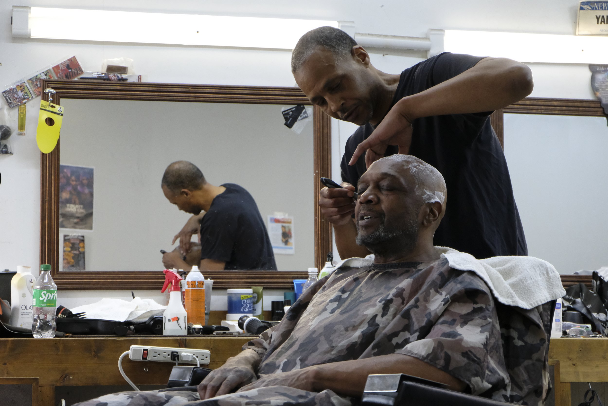  Barber Dexter Bullock uses a razor to shave a patron's head at Blue Brothers Barber Shop on South Salina Street in Syracuse, May 23, 2026. Photo by Zahra Perkins. 