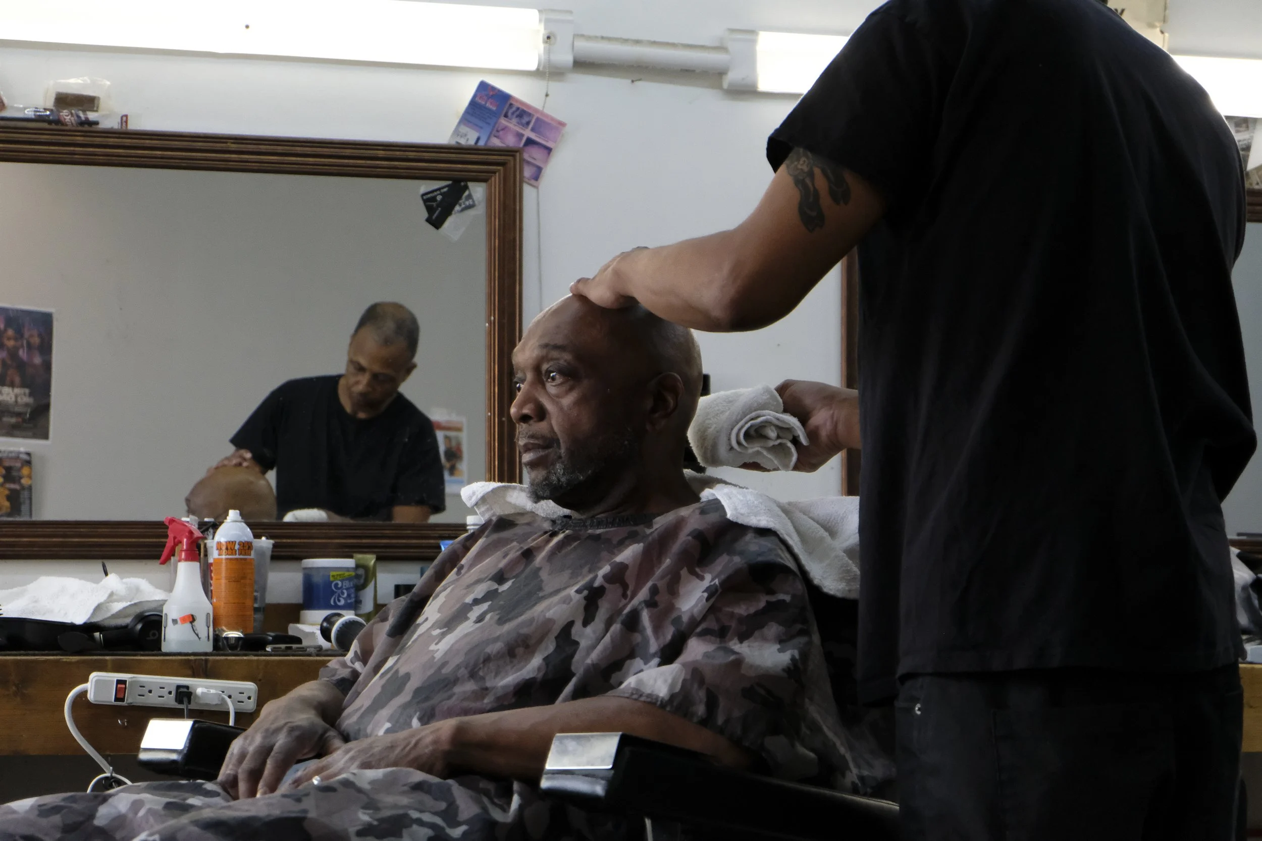  Dexter Bullock is seen shaving a patron in the mirror's reflection at Blue Brothers Barber Shop on South Salina Street in Syracuse, May 23, 2026. Photo by Zahra Perkins. 