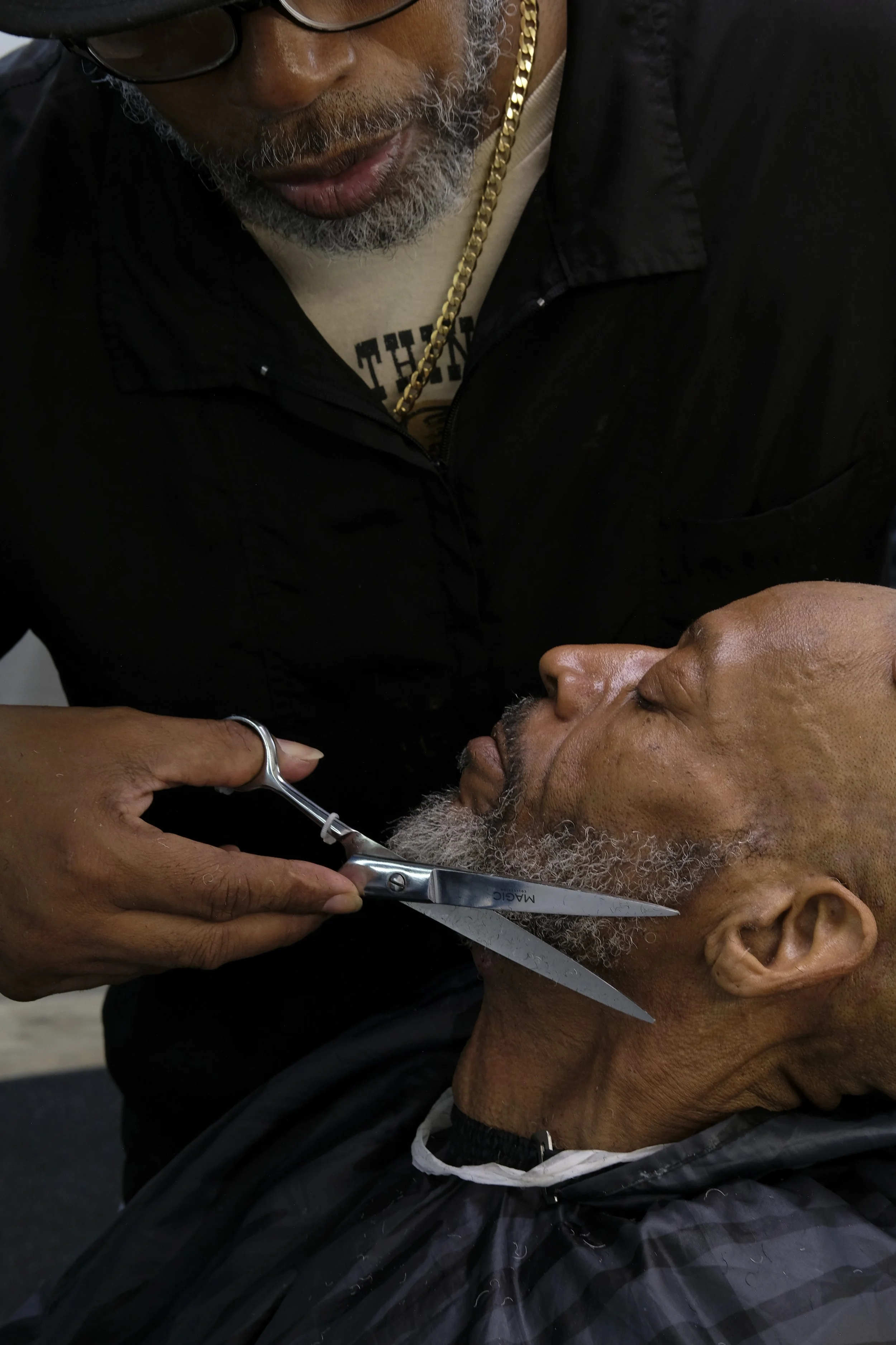  Derrick Franklin trims a patron's beard with scissors in a close-up side profile, at Blue Brothers Barber Shop on South Salina Street in Syracuse, May 16, 2026. Photo by Manila Southammavong. 